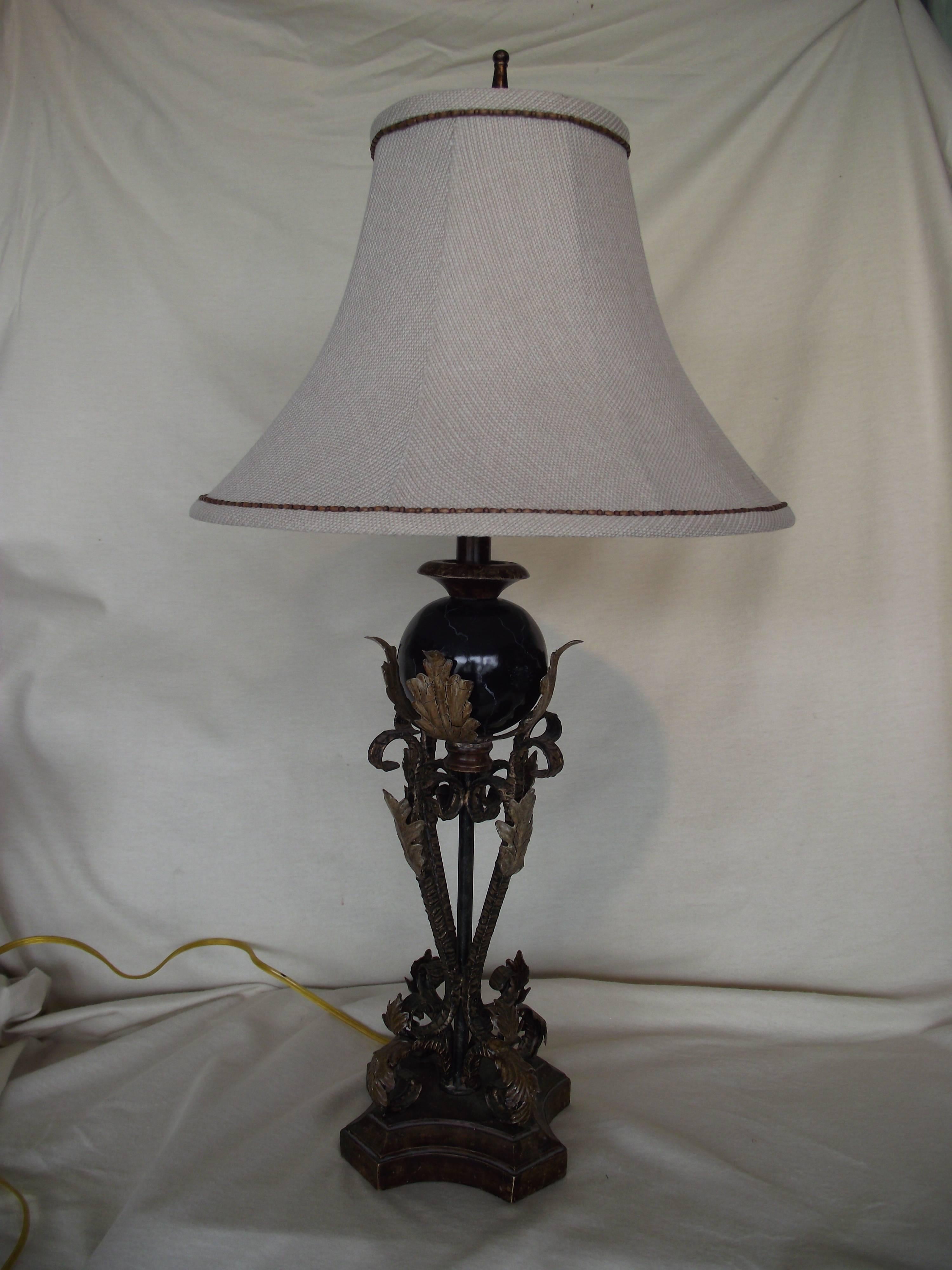 This beautiful table lamp is constructed of metal with an aged leather brown and gold leaf finish.

It features a black faux marble ball surrounded by gold leaf acanthus leaves.

It measures 33