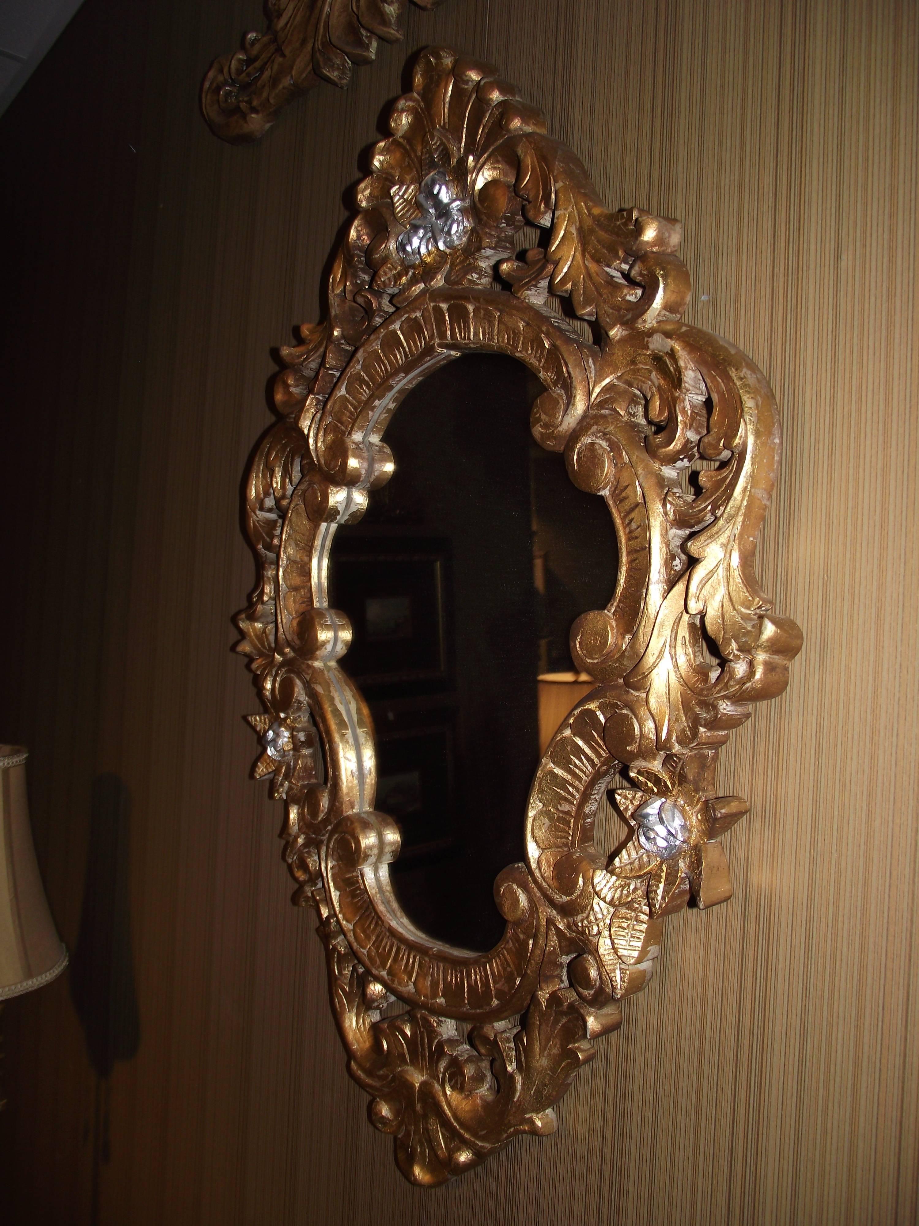 This beautiful mirror is hand-carved wood, gold leafed with silver accents.

As the pictures show it has intricate and rich detailing.
