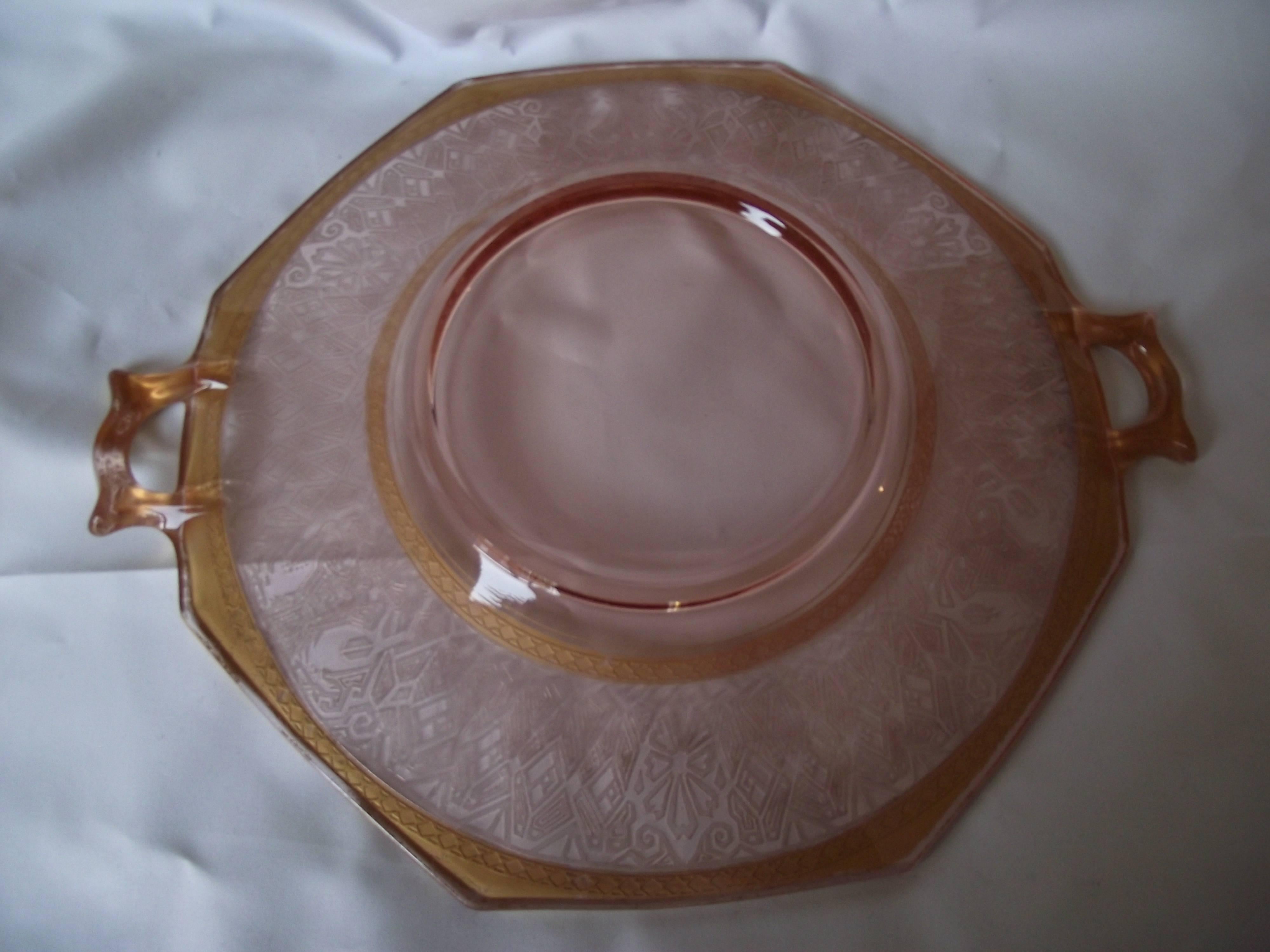 So many beautiful design elements are incorporated into this plate.

It has an octagonal shape with gold handles. The inner shape is round and is decorated with a wide faux etched glass, Egyptian style border.

Two bands of applied gold diamonds