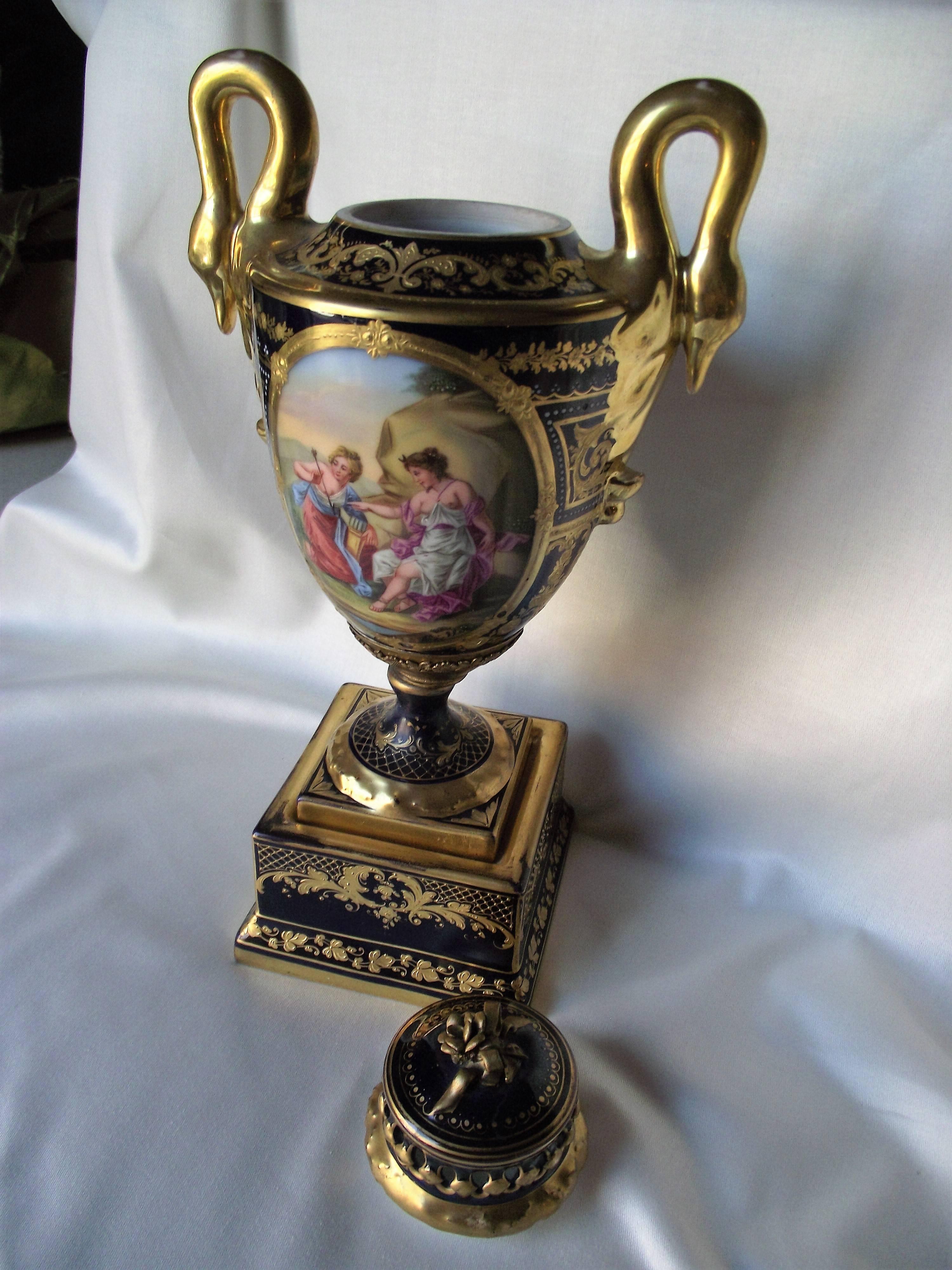 This exquisite Royal Vienna vase features hand-painted scenes of Aphrodite and cupid and a girl with Roman solders. Except for some wear to the gold on the base it is in very good condition. It has swan handles.

No chips or cracks. The lid has a