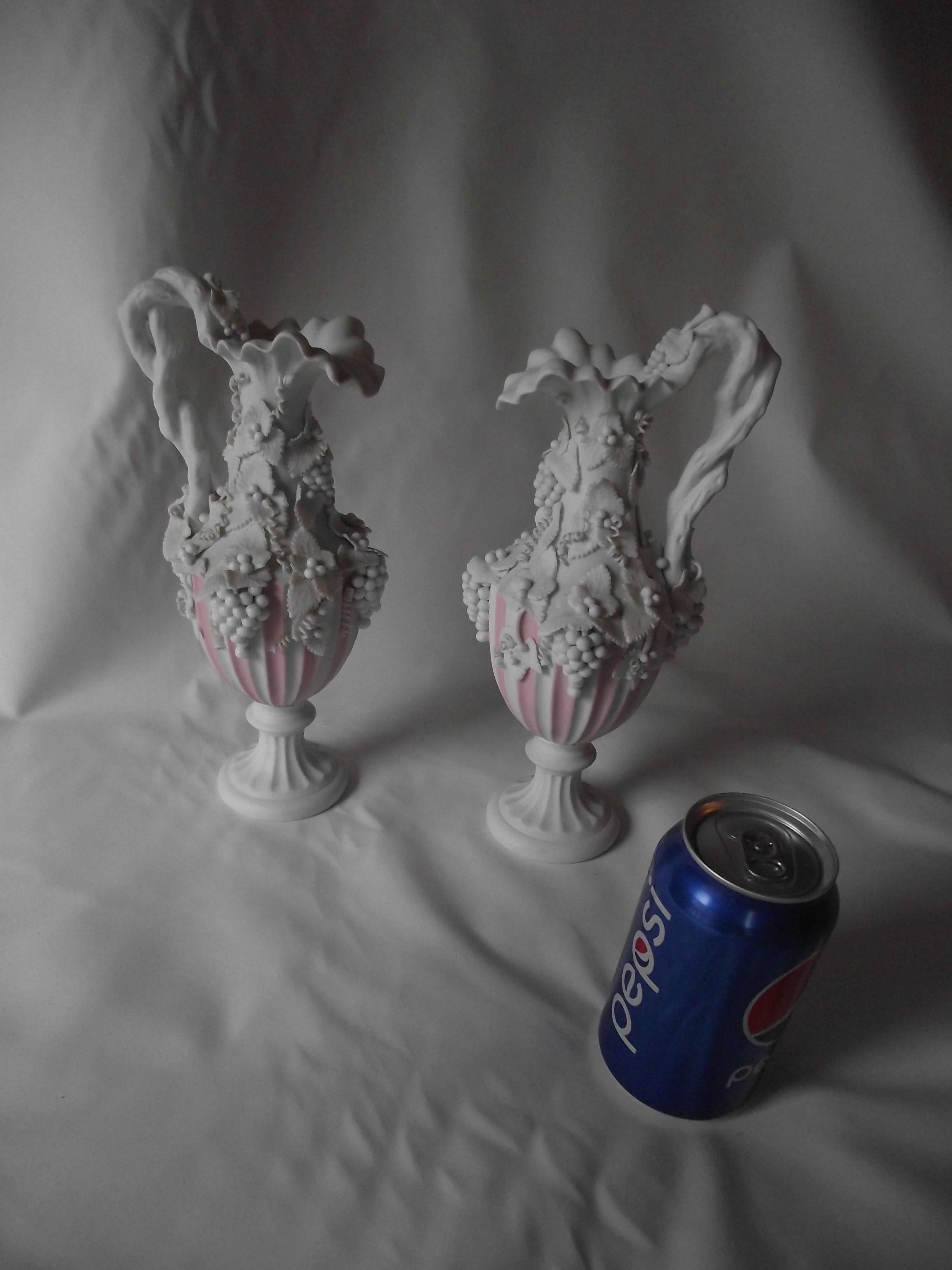 Highly ornamented with a grape and vine theme, these Parian urns are delicate little beauties.  They have a soft pink and white stripe on the bottom half giving the a touch of color.

Barely noticeable damage to two of the little grape leaves