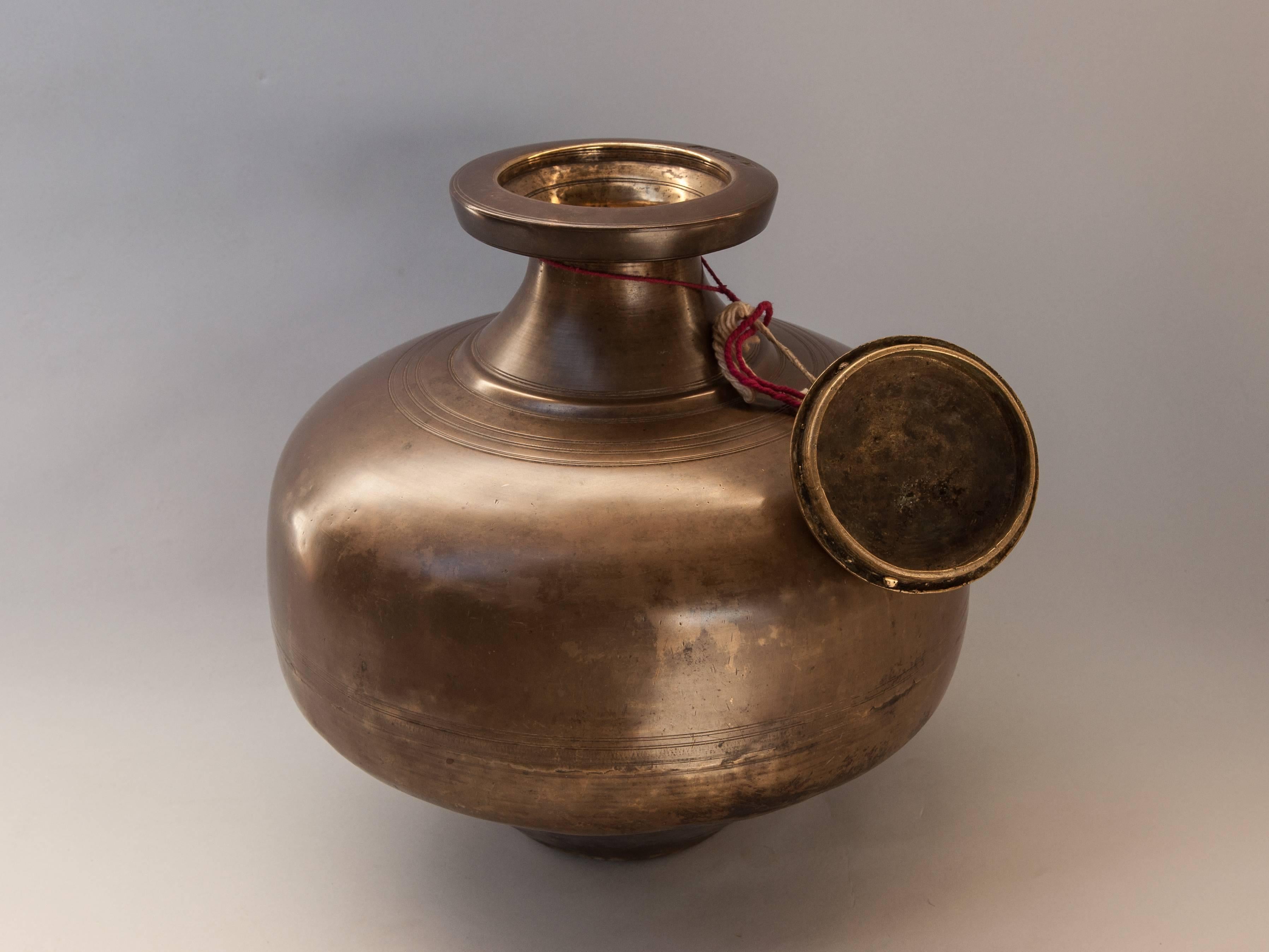 Bengali Brass Water Pot with Cap. Early-Mid 20th Century. Bengal, India.
Offered by Bruce Hughes.
This beautifully shaped and heavy brass or bronze vessel was used to store water, to keep it cool and ritually pure. 
Dimensions: 13.5 inches diameter