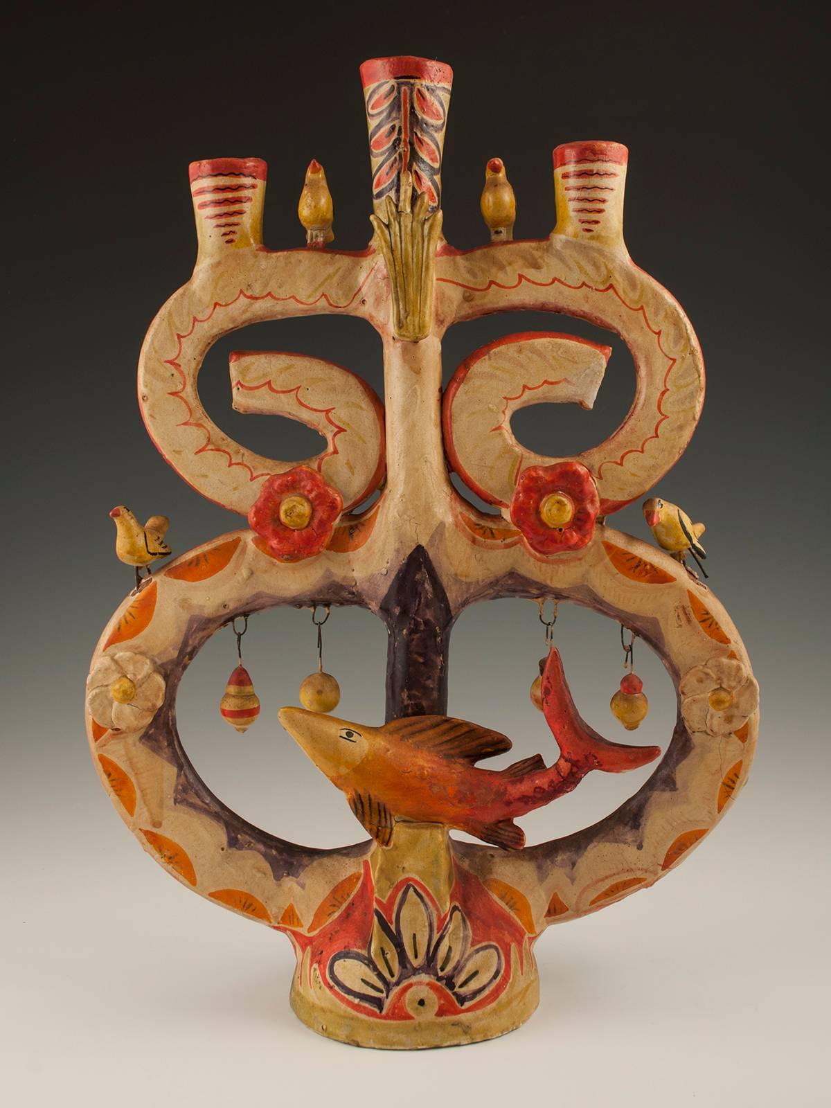 Mid-century Folk Art Candelabra by Aurelio Flores, Izucar de Matamoros, Mexico 

A candelabra featuring a large fish, birds, flowers and dangling ornaments. The fish's tail has been repaired, as has the center bit of the flame near the top,