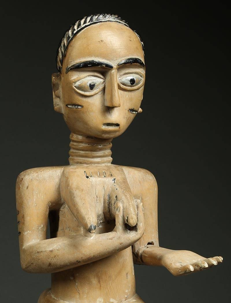 Stehende weibliche Figur aus Akan Ghana, frühes 20. Jahrhundert, Afrika. Intensiver Ausdruck mit großen Augen.
Weibliche Figur mit einer Hand auf der Brust, die die Übergabe von Nahrung durch die Ahnen darstellt.  Ein ausgestreckter Arm, der separat