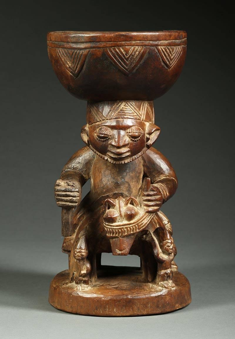 Early Yoruba offering bowl in the from of a male figure with a beard riding on horse back surrounded by four small attendants, finely carved with nice patina from native use. Probably was carrying a sword in hand, the top is now missing. Measures:
