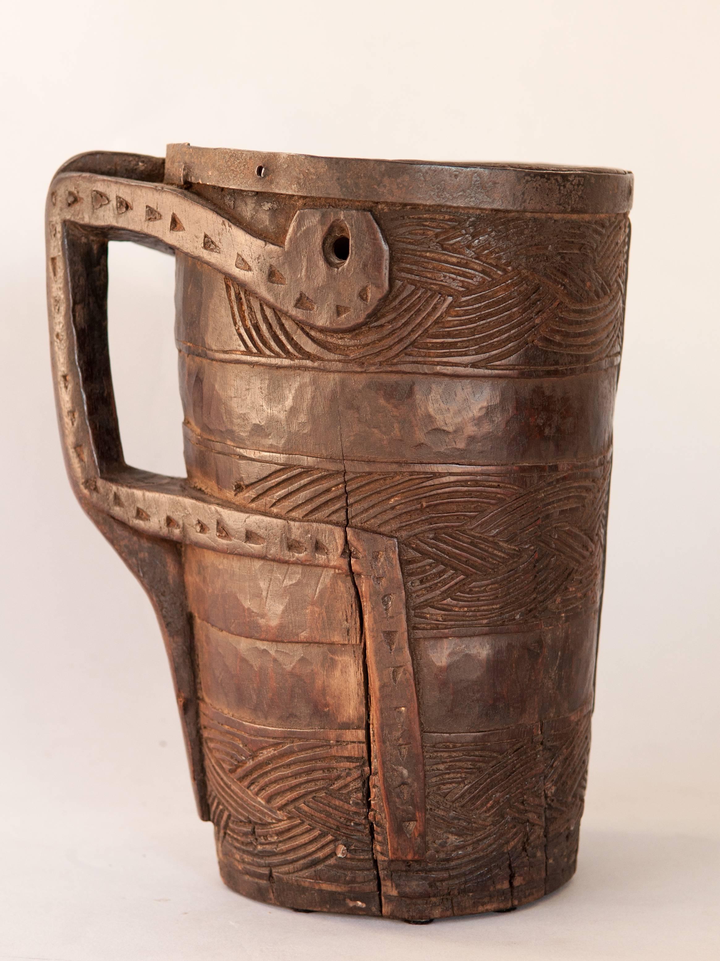 Wooden Carved Milk Pot with Stylized Monkey Motif. Late 20th Century. From the Middle Hills of West Nepal.
This rustic milk pot was hand carved of local hardwood in the middle hills of western Nepal,  using very basic tools. Geometric designs adorn