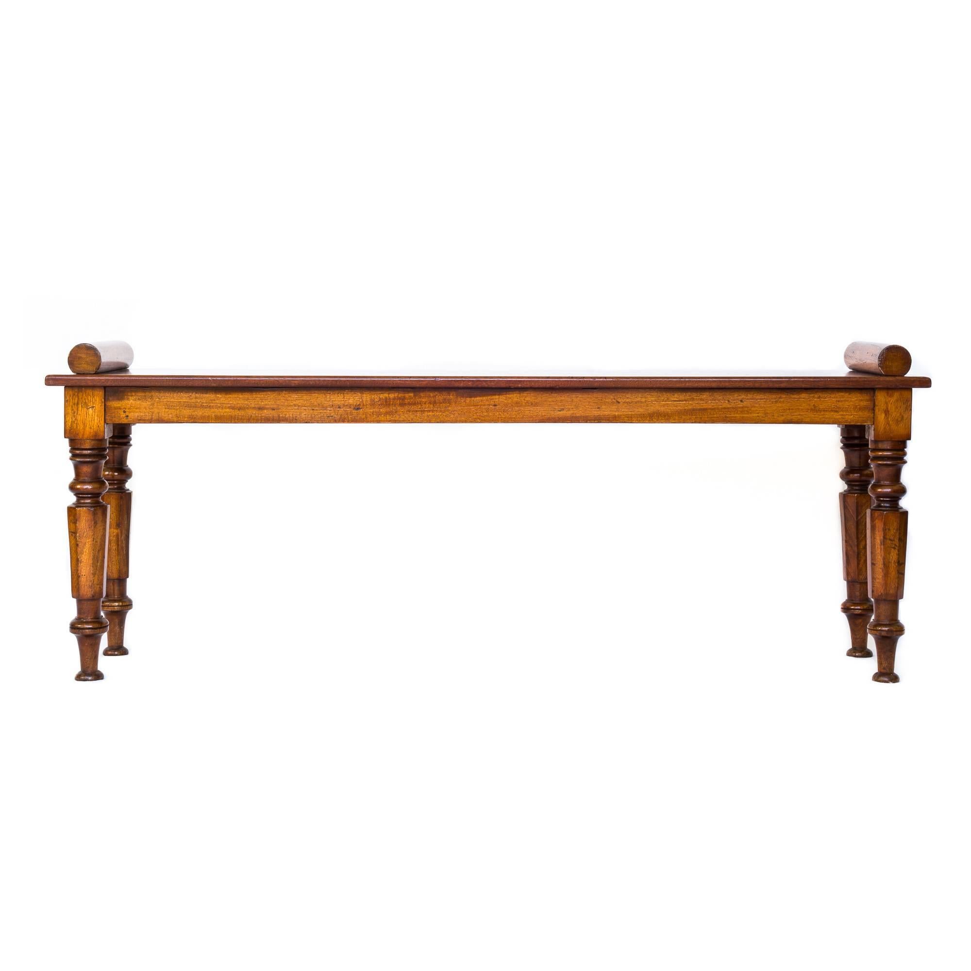 An elegant William IV and later hall bench of in beautifully grained and patinated mahogany, with bolster ends over single plank seat, raised on four turned and faceted octagonal supports. English, circa 1835.

Excellent condition, good grain and