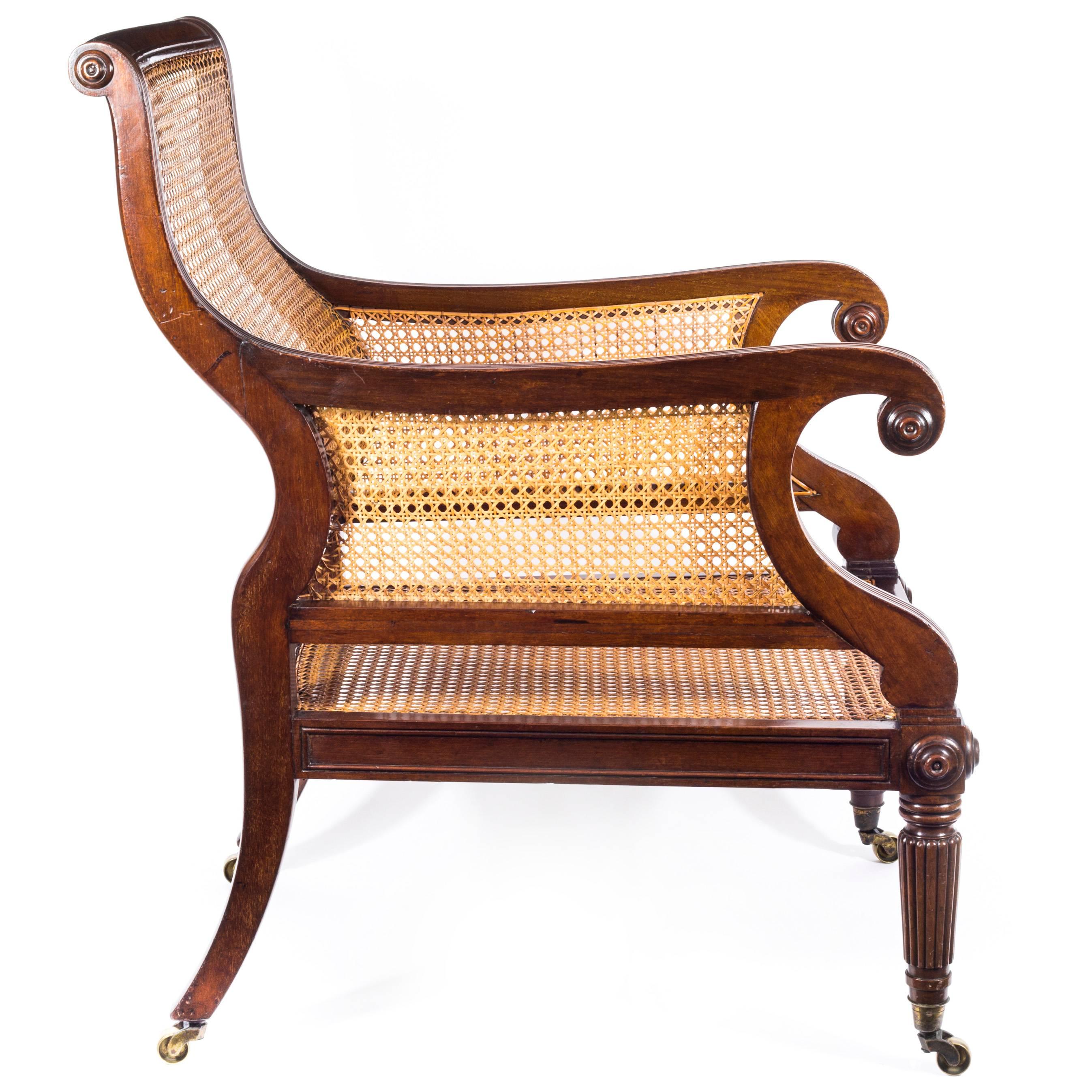 A superb early Regency period library bergère armchair in mahogany, attributed to Gillows of Lancaster and London

English, circa 1810

The curved blind-caned back within a moulded frame and reeded scrolled blind-caned arms, above a rectangular