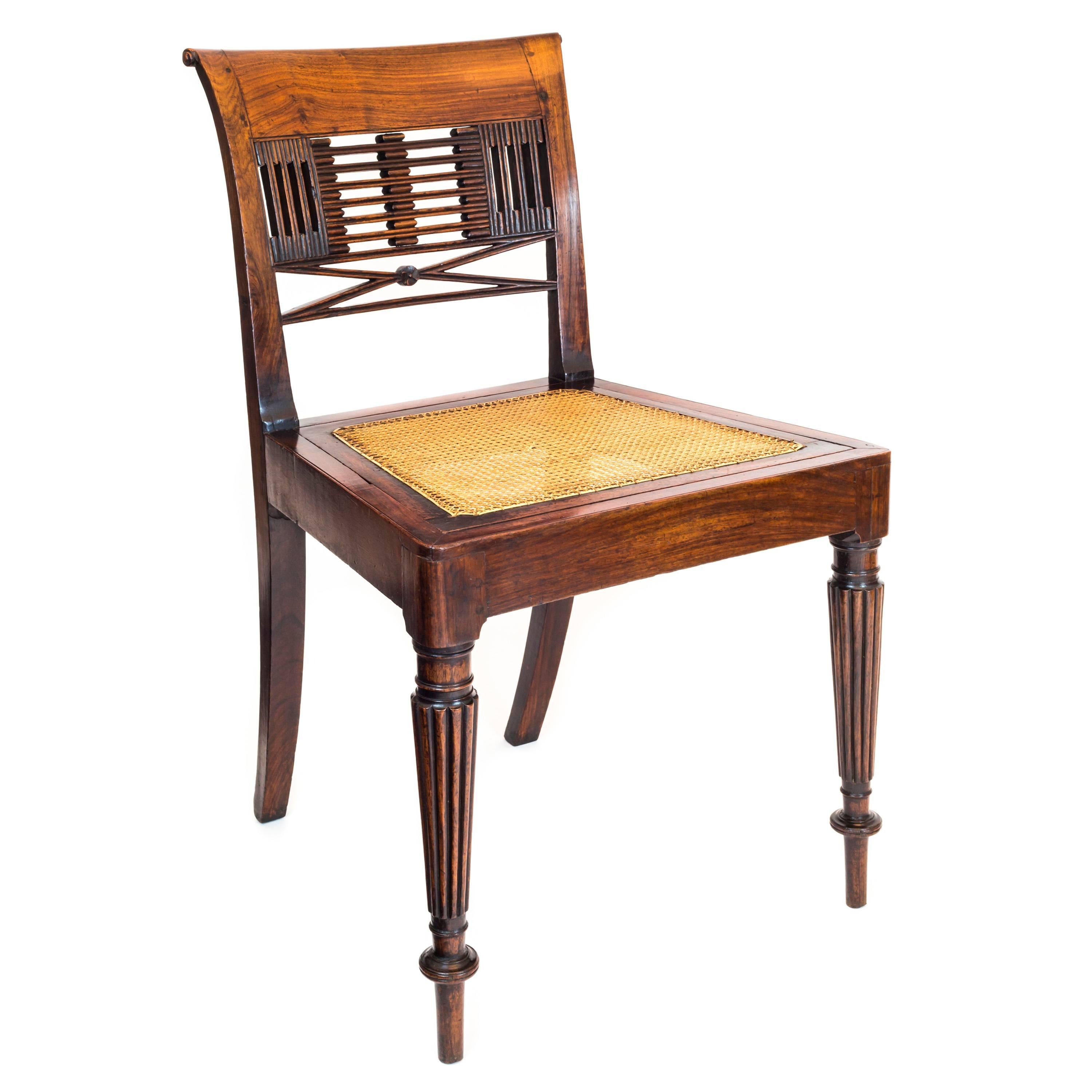A rare Regency period colonial side chair in solid padouk, made for English market,

Anglo-Chinese, circa 1825.

Having a curved and scrolled top rail, the pirced and carved back splat, above the finely caned drop-in seat, within the solid