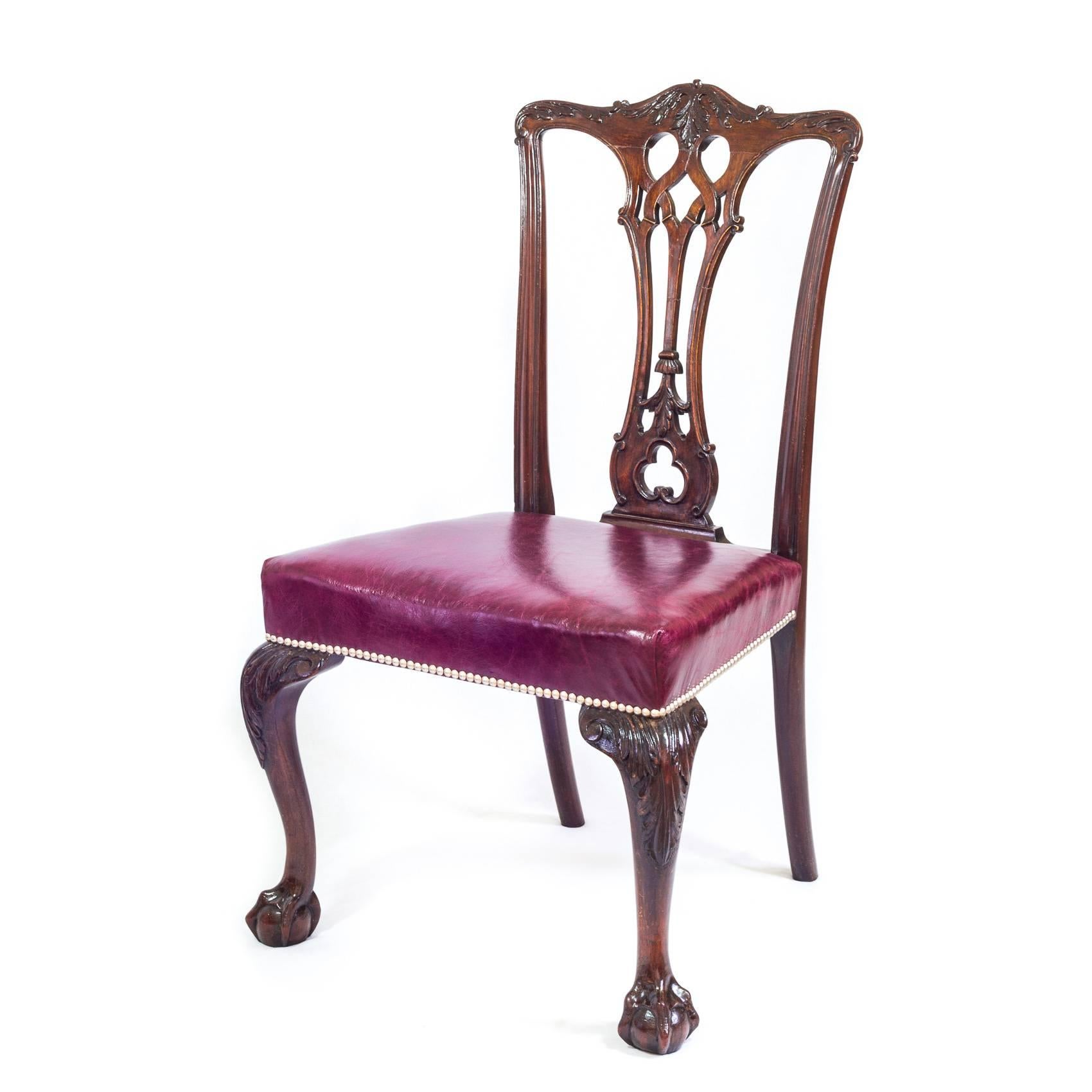 A good late 19th century set of four generously proportioned mahogany dining chairs in the Gothic Chippendale taste, with pierced splats of gothic inspiration below the top rail carved with acanthus scrolls, the stuff-over seats covered in Burgundy