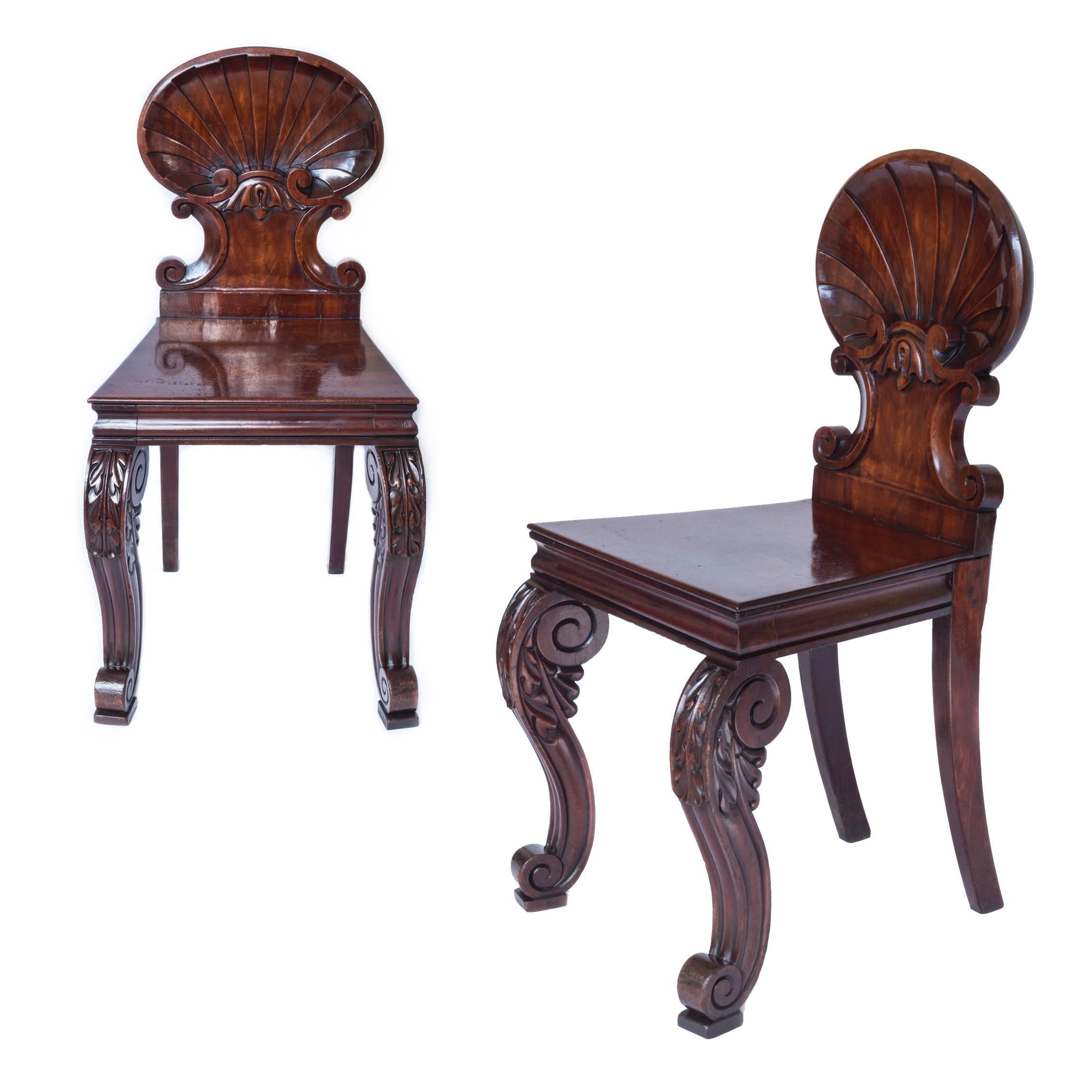 Rare and unusual pair of late Regency - William IV period mahogany hall chairs, in the Kentian baroque-revival taste, after a design by Gillows of Lancaster and London.

Possibly Irish, c. 1835.

Each chair having the scalloped shell carved back,