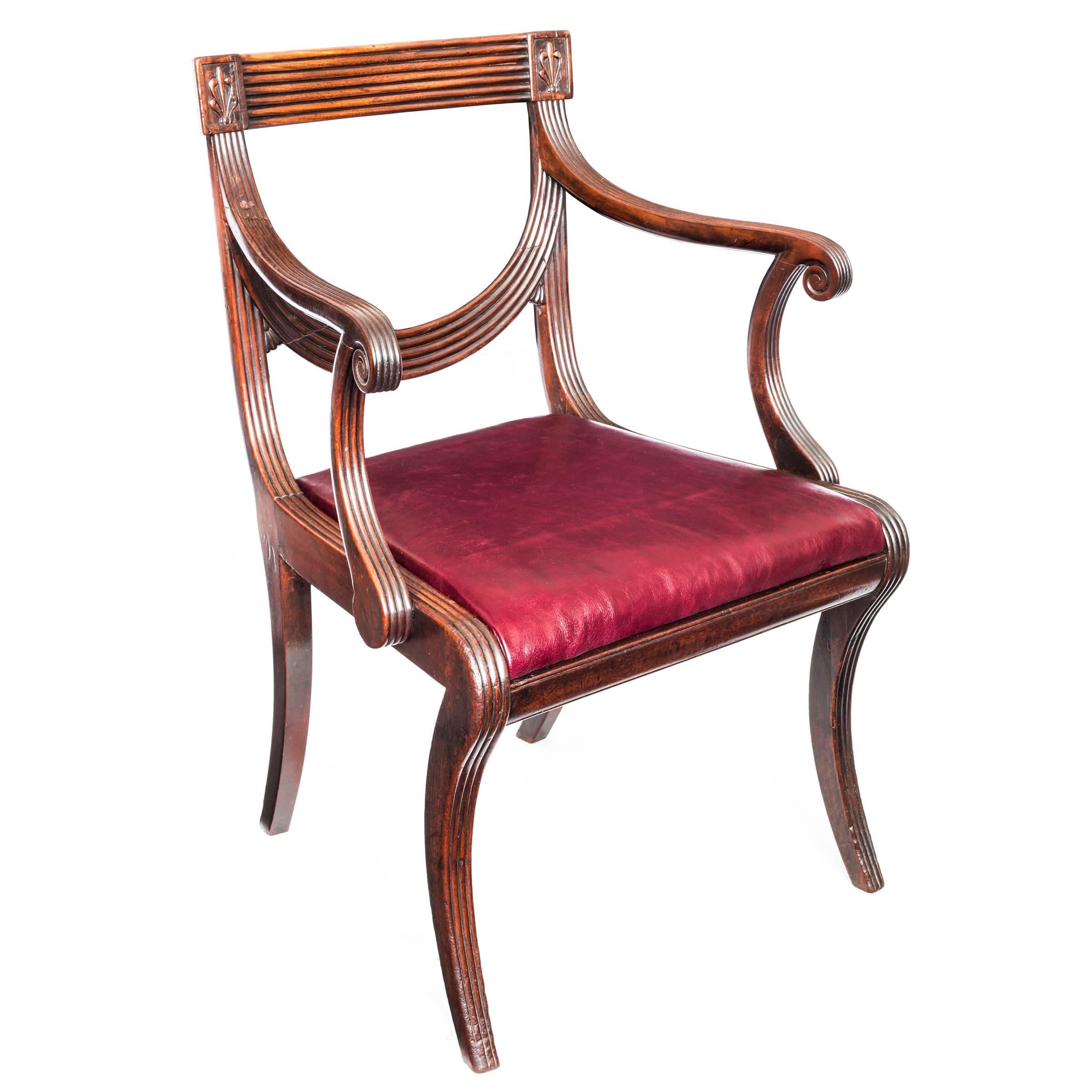 Fine early 19th century Regency desk armchair of Grecian Klismos form in mahogany, after Thomas Sheraton's design.

English, circa 1810.

Reeded overall, with a concave rectangular toprail, flanked by anthemion carved tablets, above a U-shaped