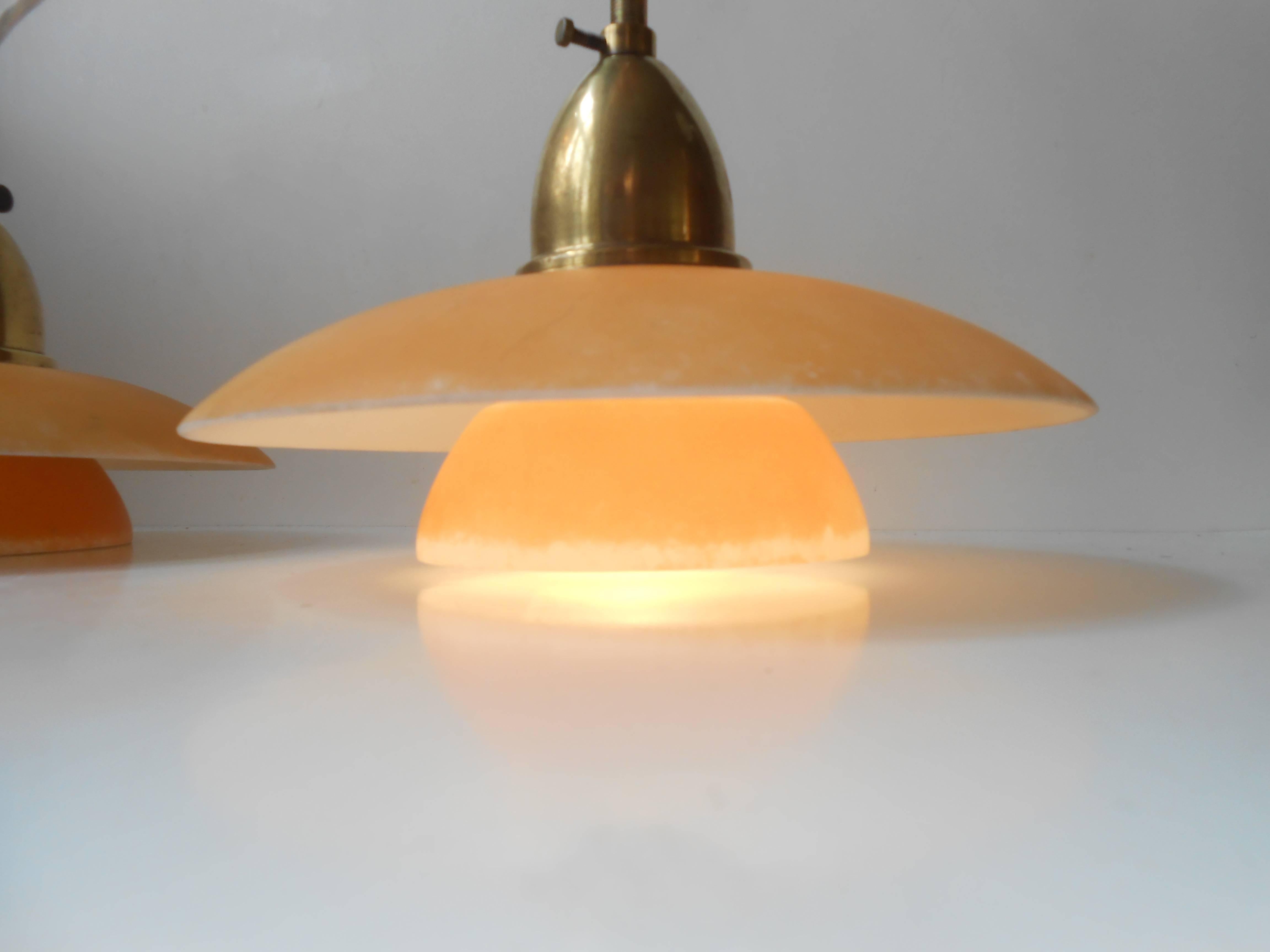 Very early and delicately constructed pair of single layered dusty yellow glass and brass pendant lamps by Lyfa, Denmark, circa 1930. Very close resemblance the early designs of Poul Henningsen. These have been electrically restored with new wires