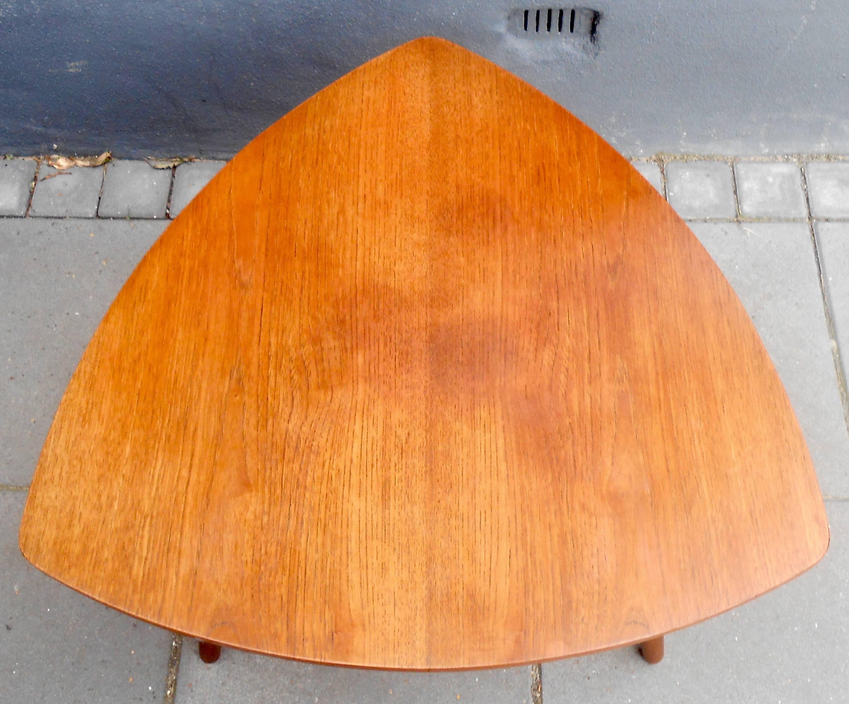 This small teak coffee table in the shape of a guitar pick was manufactured in Denmark during the early 1960s. The designer/maker is un-identified. Measurements: 24 x 24 inches with a height of 19 inches. The table will be shipped with its legs