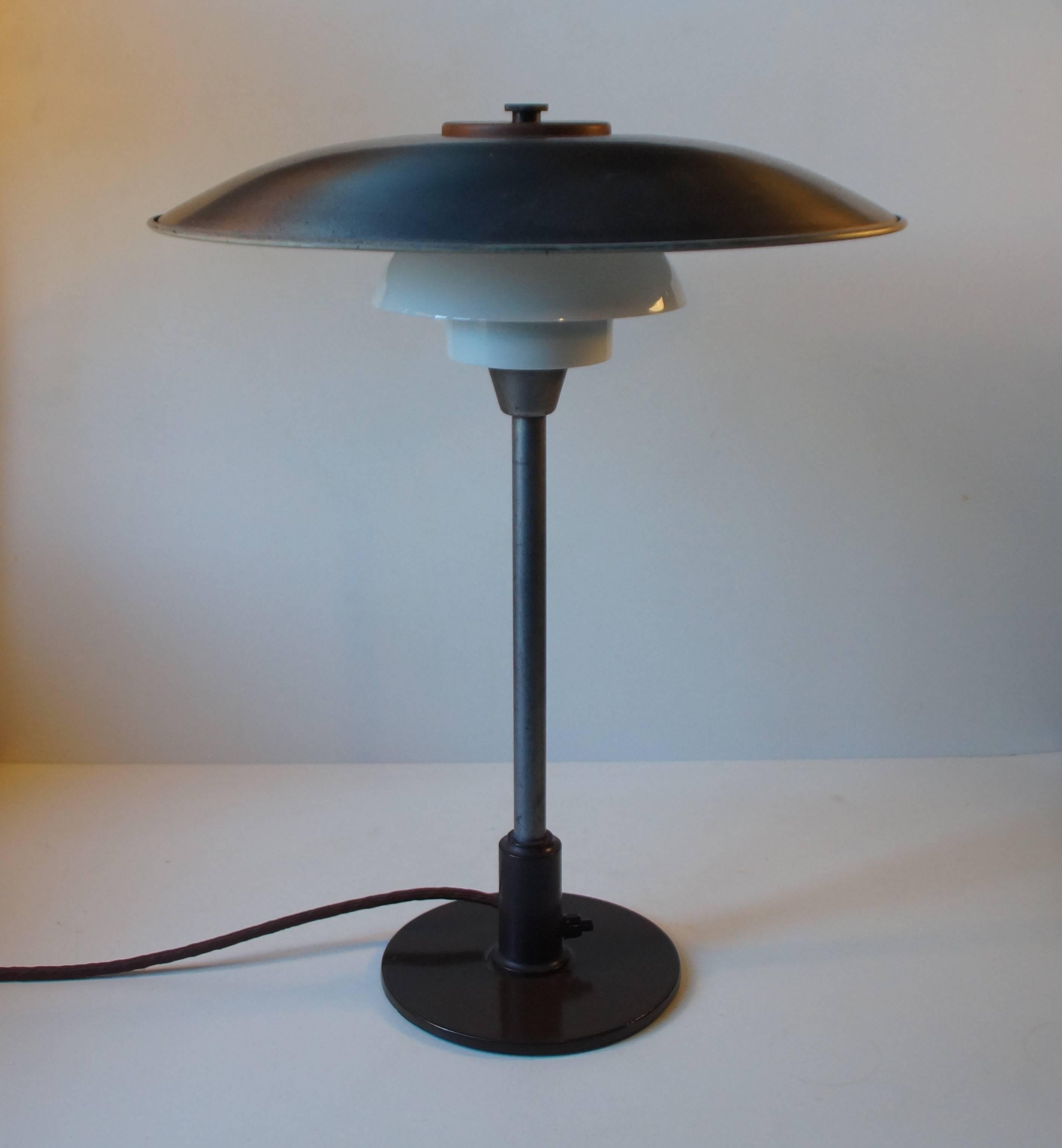 Poul Henningsen 3,5/2,5 table lamp with zinc main shade, single-layer opaline glass middle- and bottom shade and switch and socket house made of bakelite. The lamp is fully restored with the raw zinc exposed and highlighted with clear lacquer to the