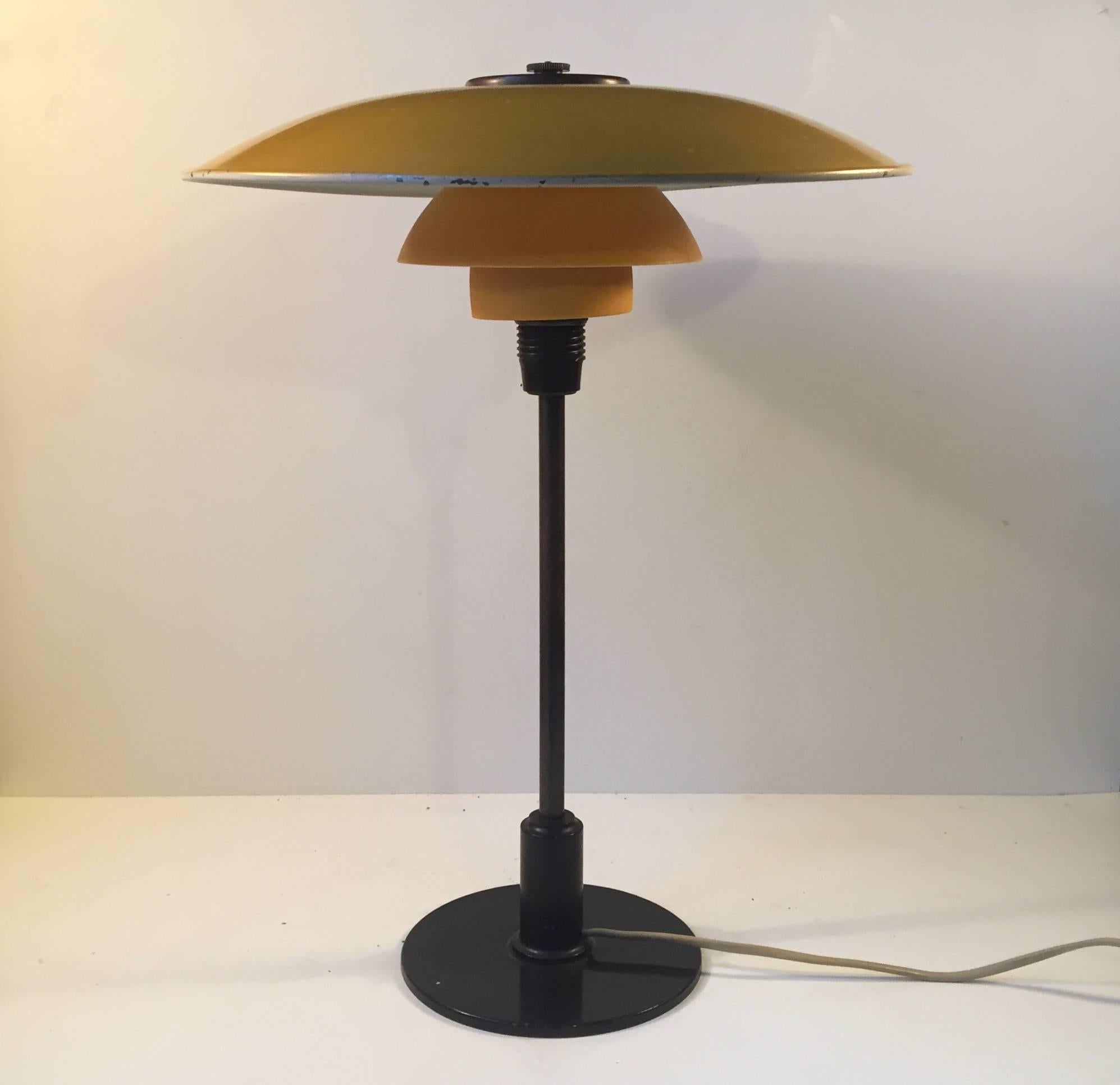 PH 3½-2 desk light by Poul Henningsen. Original yellow lacquered zinc top-shade, matté yellow single layered glass middle and bottom shade, patinated brass stem and Bakelite detailing. Manufactured by Louis Poulsen in Denmark circa 1930. Fine