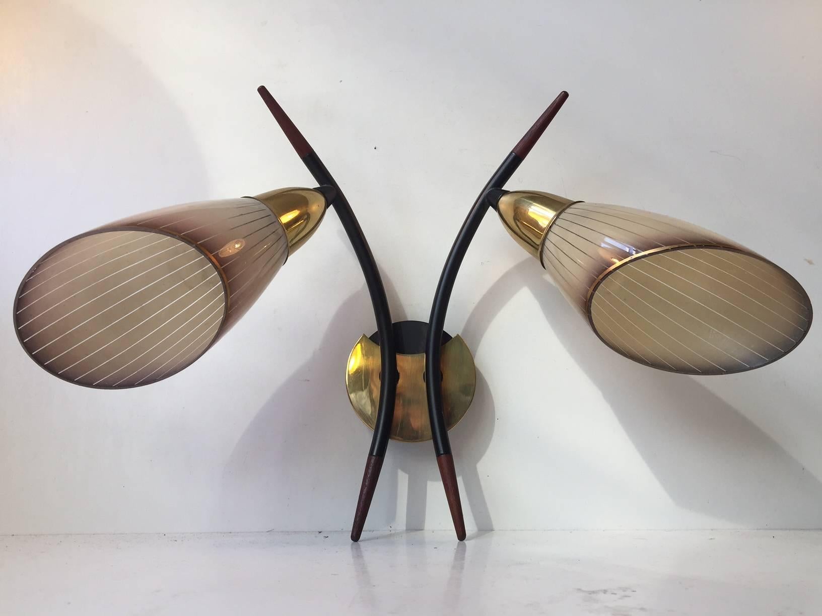 Twin sconce designed in a style reminiscent of Stilnovo and manufactured in the 1950s by anonymous Italian maker/designer. It is made from brass; black powder coated steel and striped colored glass. Teak accents to the arching black arms are a