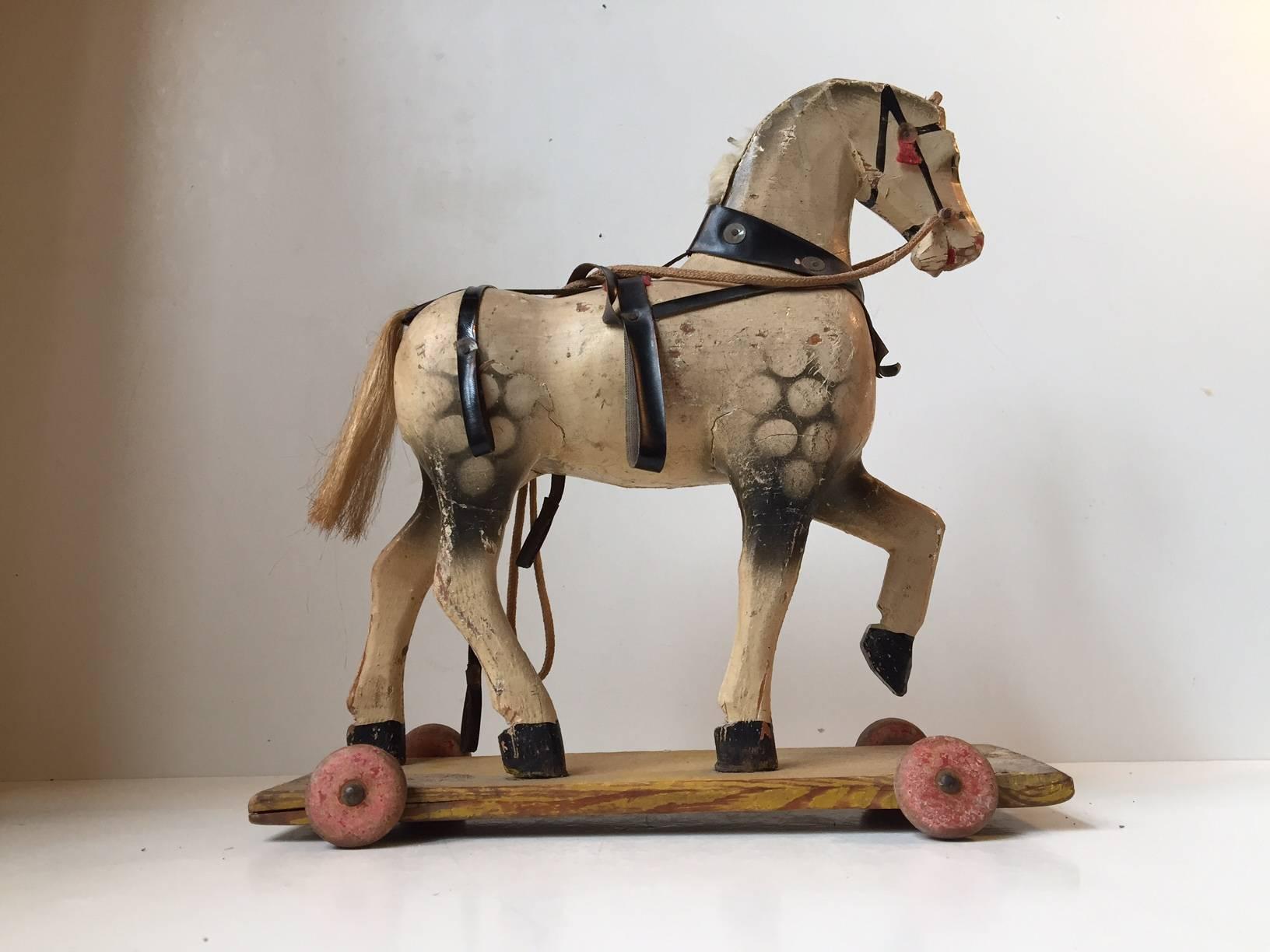 Despite the shabby chic appearance this old hand-carved wooden horse on wooden wheels remains fully functional. Crafted in Germany during the 1930s. Richly patinated from top to bottom. Measure: Height 27 cm (10.6 inches), width 24 cm (9.5 inches).