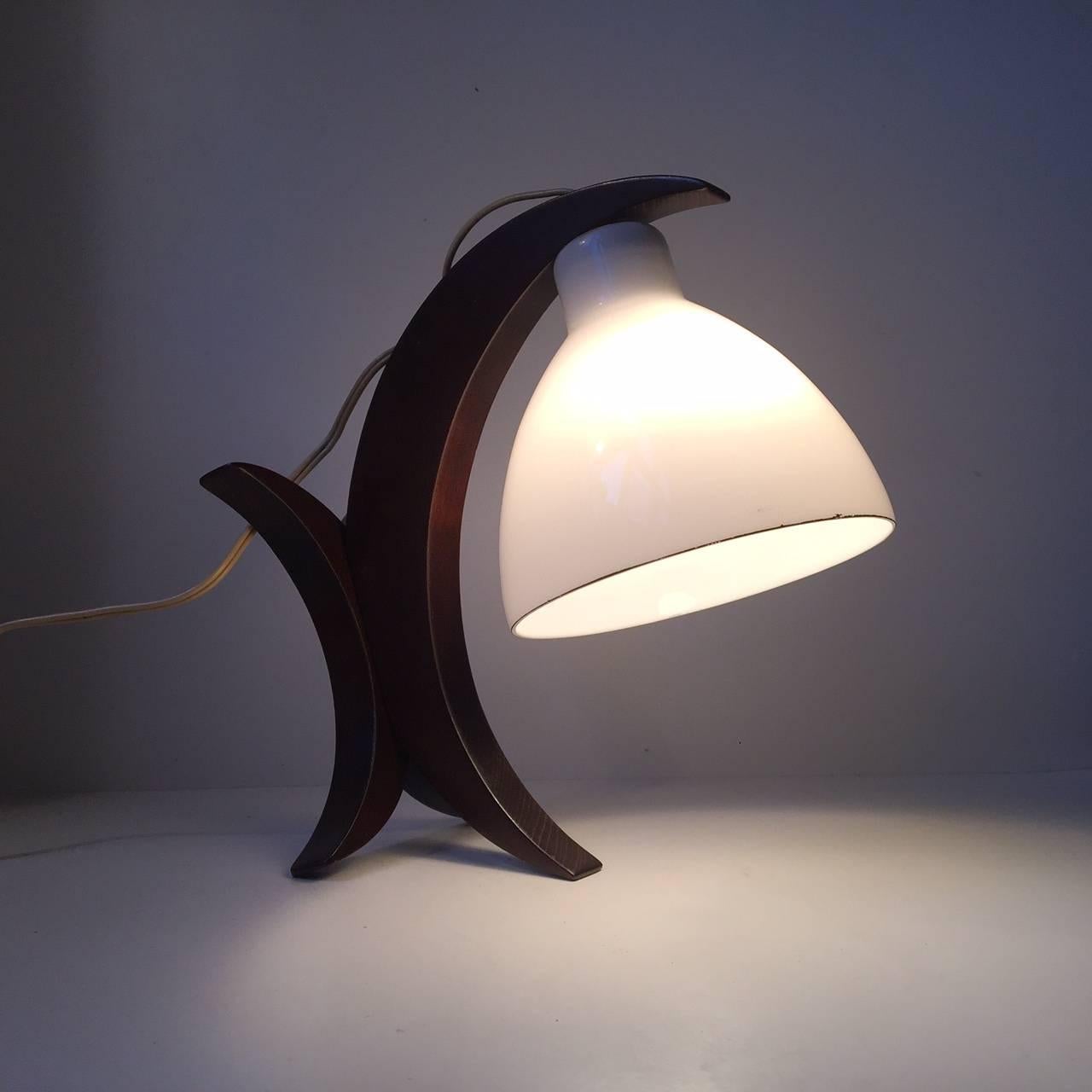 Designed and manufactured anonymously during the 1950s by a German Craftsman this Dual-purpose Table Light or Sconce constructed of an opaline glass shade and lacquered oak frame composed of three Half Moon 's is indeed aesthetically pleasing to the