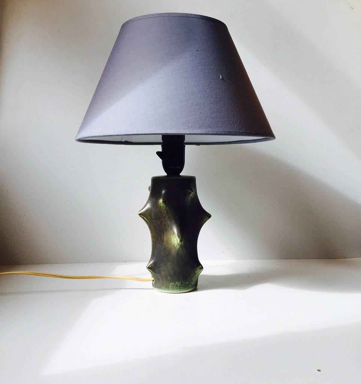 The Rose Thorn table lamp was designed by Knud Basse. It was manufactured in Denmark by Michael Andersen & Son during the 1950s. It features a warm black colored glaze with light green glaze peeking out here and there. The huge popularity of the