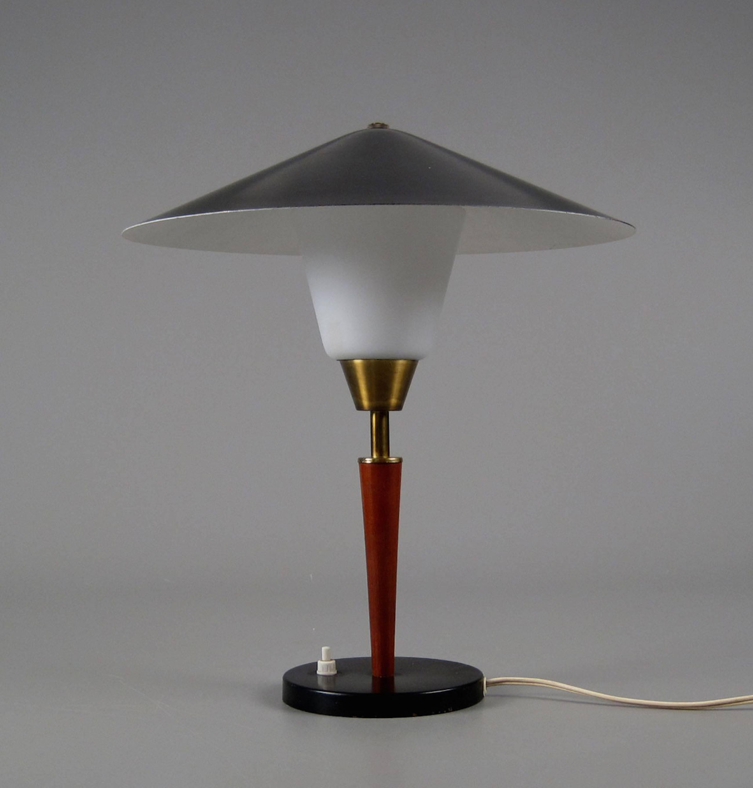 1950s desk lamp designed and manufactured by Fog & Mørup in Denmark. Black metal base and shade with reflective white interior over a conical inner-shade in opaline glass. Stem in teak and slightly patinated brass. Fine intact 1950s condition with