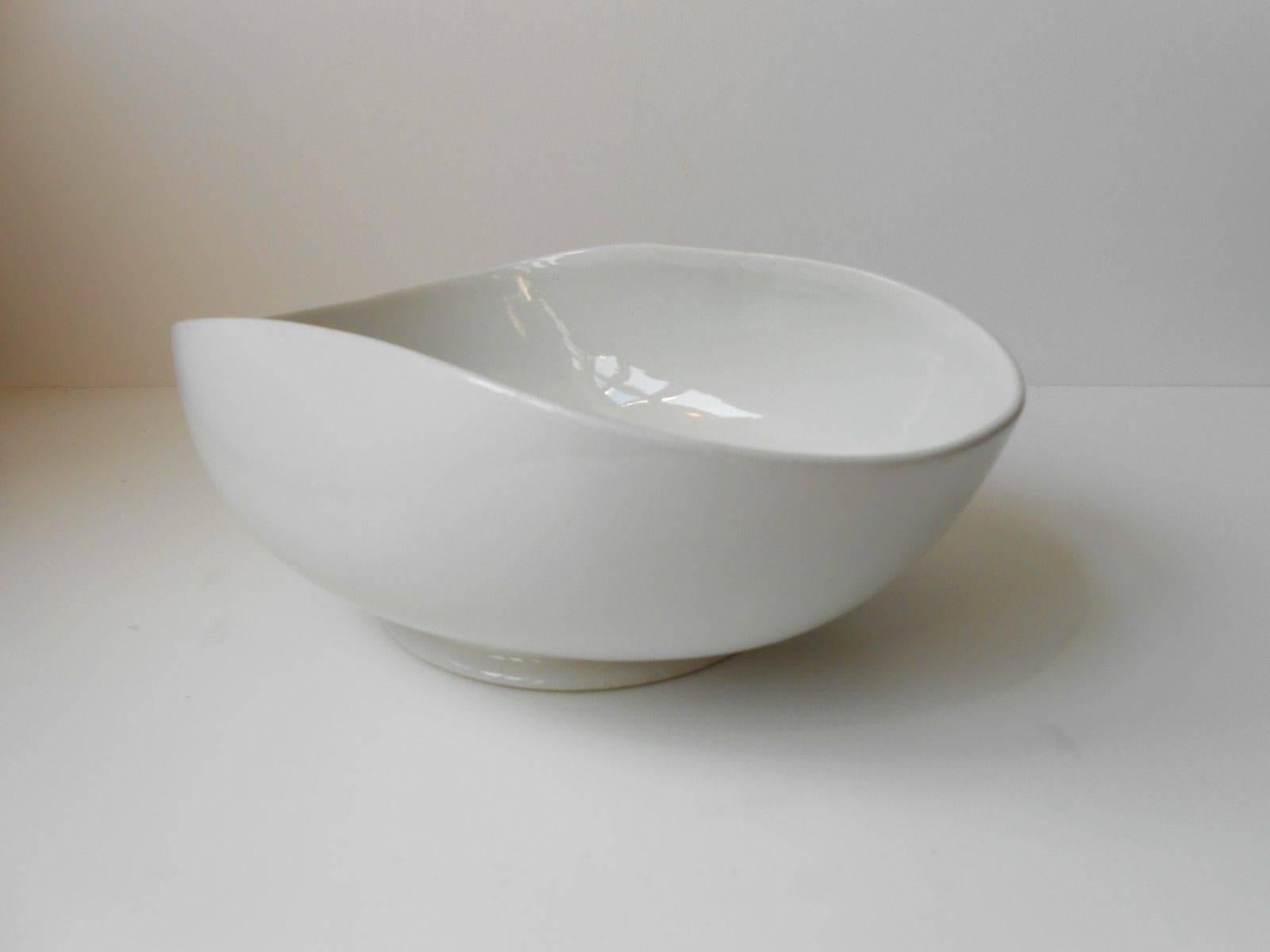 This rare curved white glazed ceramic bowl was designed in 1938 by the Swedish ceramist Wilhelm Kåge. It's a part of the soft forms lin (Fin: Mjuka Formernas). The open organic and biomorphic design, while strikingly simple, was ingeniously