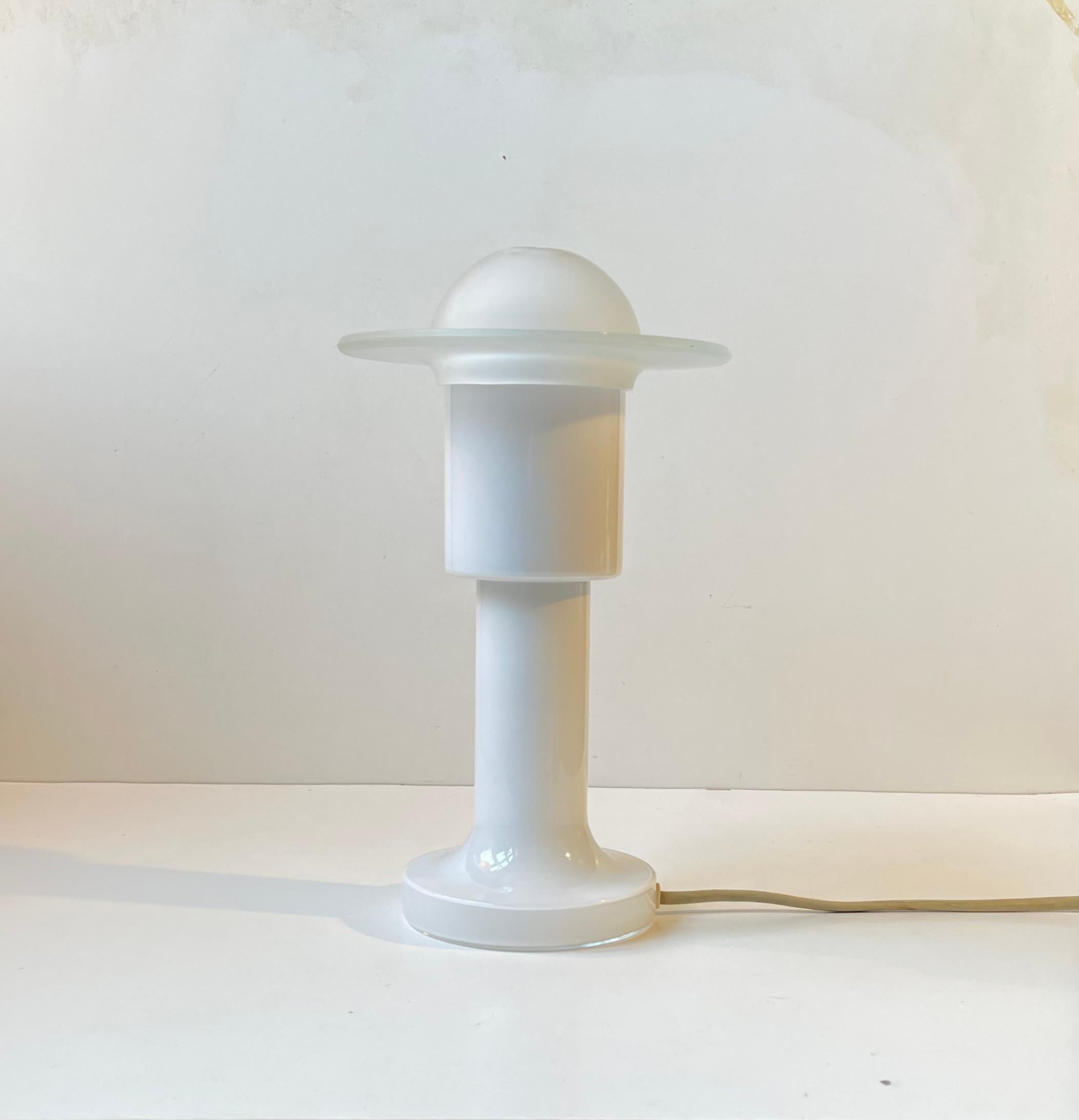 An elegant space age table light made from white opaline glass and featuring an UFO shaped shade in frosted glass. The base was made at Holmegaard in Denmark during the 1970s. Working condition. 

Measurements: H: 30 cm, Diameter: 15 cm (shade). 