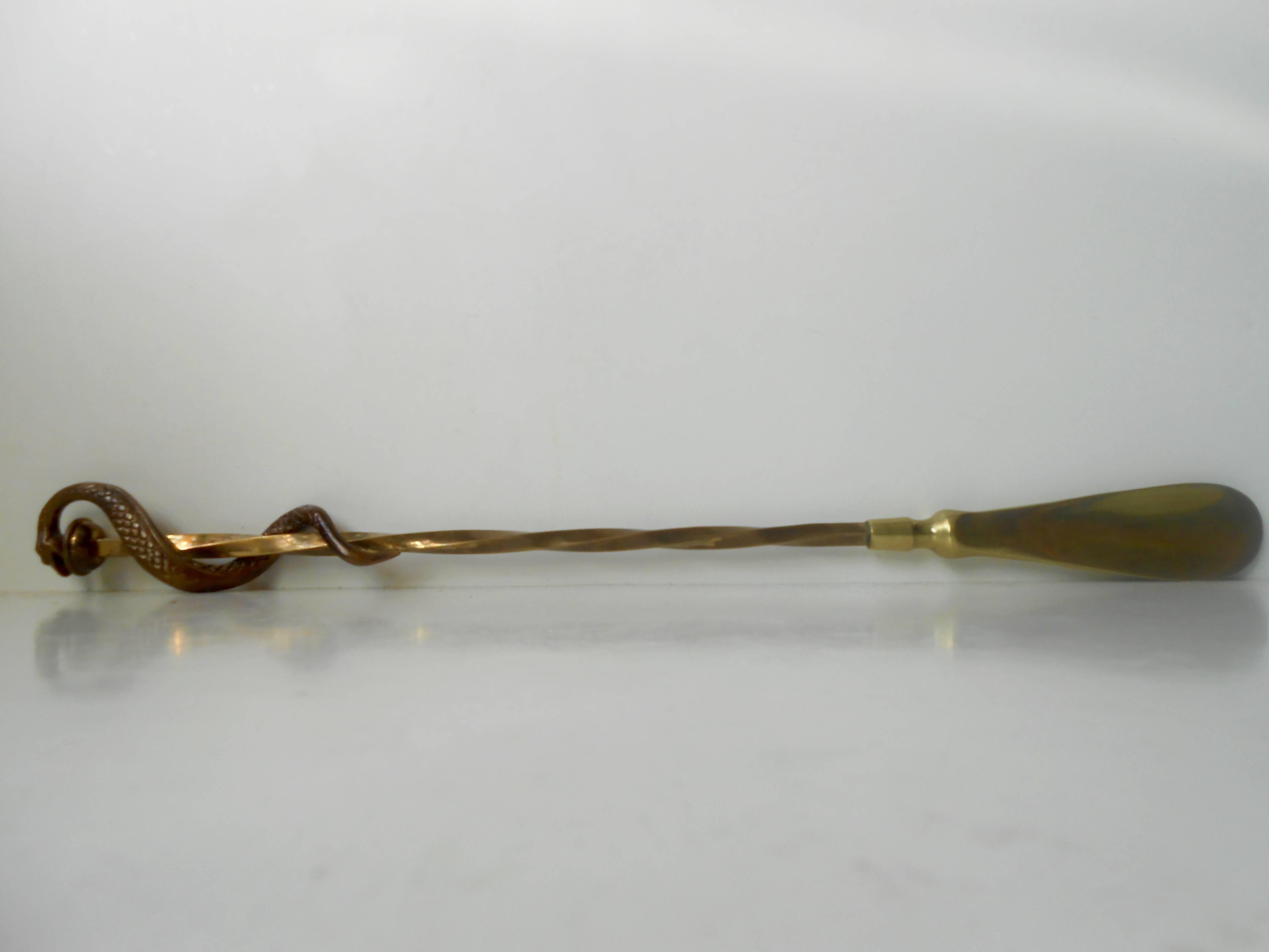 Ornate and stylistically unusual long handled shoe horn made of solid brass. The handle or top has a coiling bronze snake (6 inch in length). It was made in Europe during the 1930s by anonymous maker.