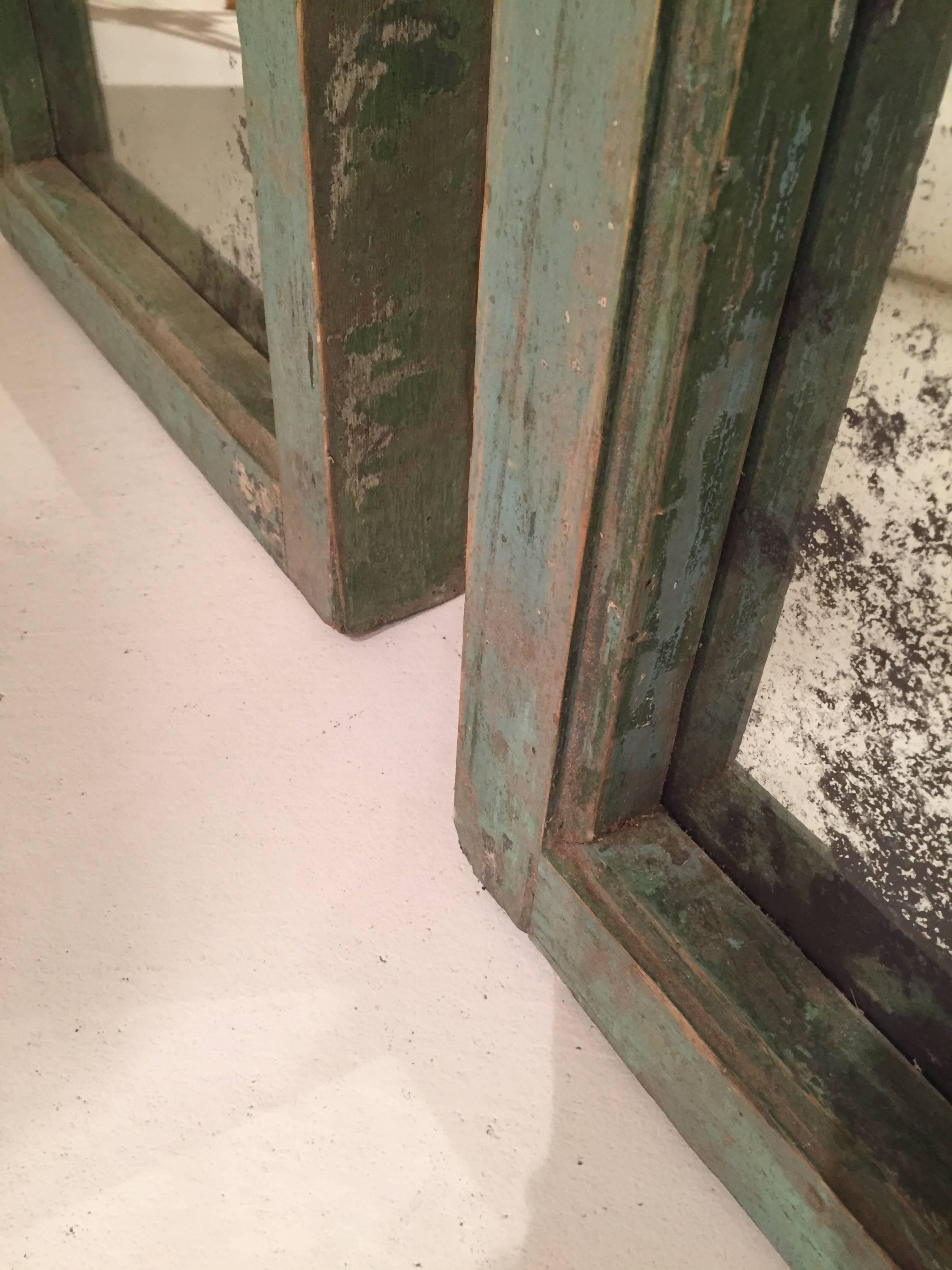 Pair of green Spanish wooden trumeau mirrors with antiqued and distressed mirror.