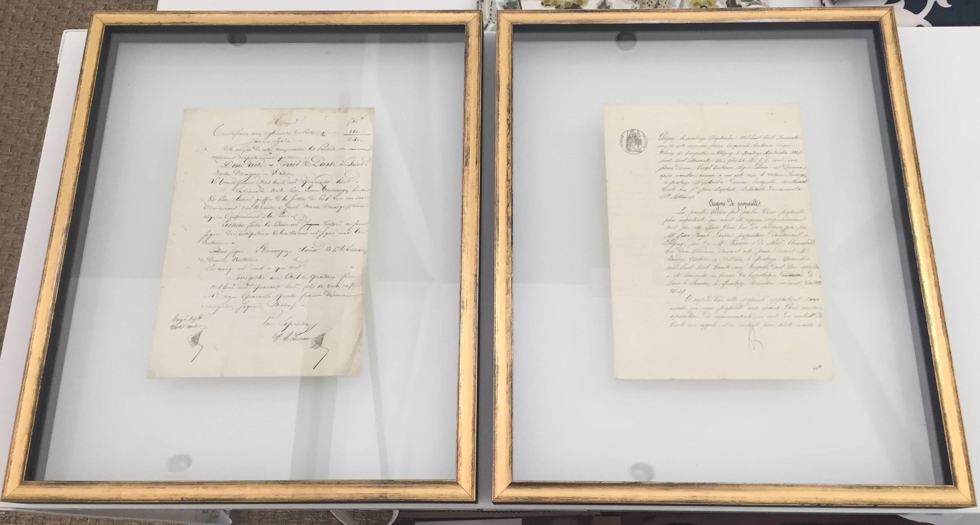 Pair of floating French manuscripts between two panes of glass in gold with black edged shadow box frames.