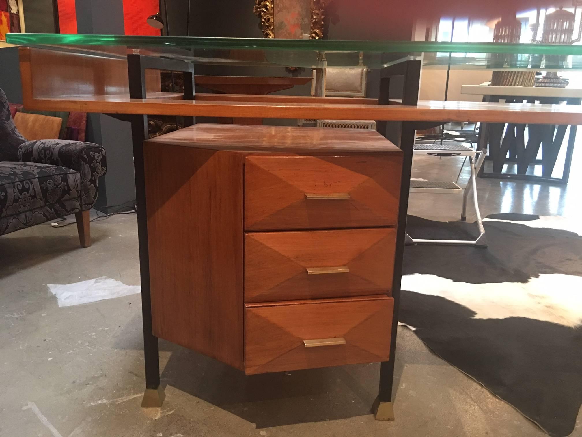 Its body configured in the shape of a chevron. Its drawer compartments exhibiting pyramidal relief detail, embellished by pulls, all below a floating glass top. The whole supported by black steel legs.

Italy, (Milan) 1955.