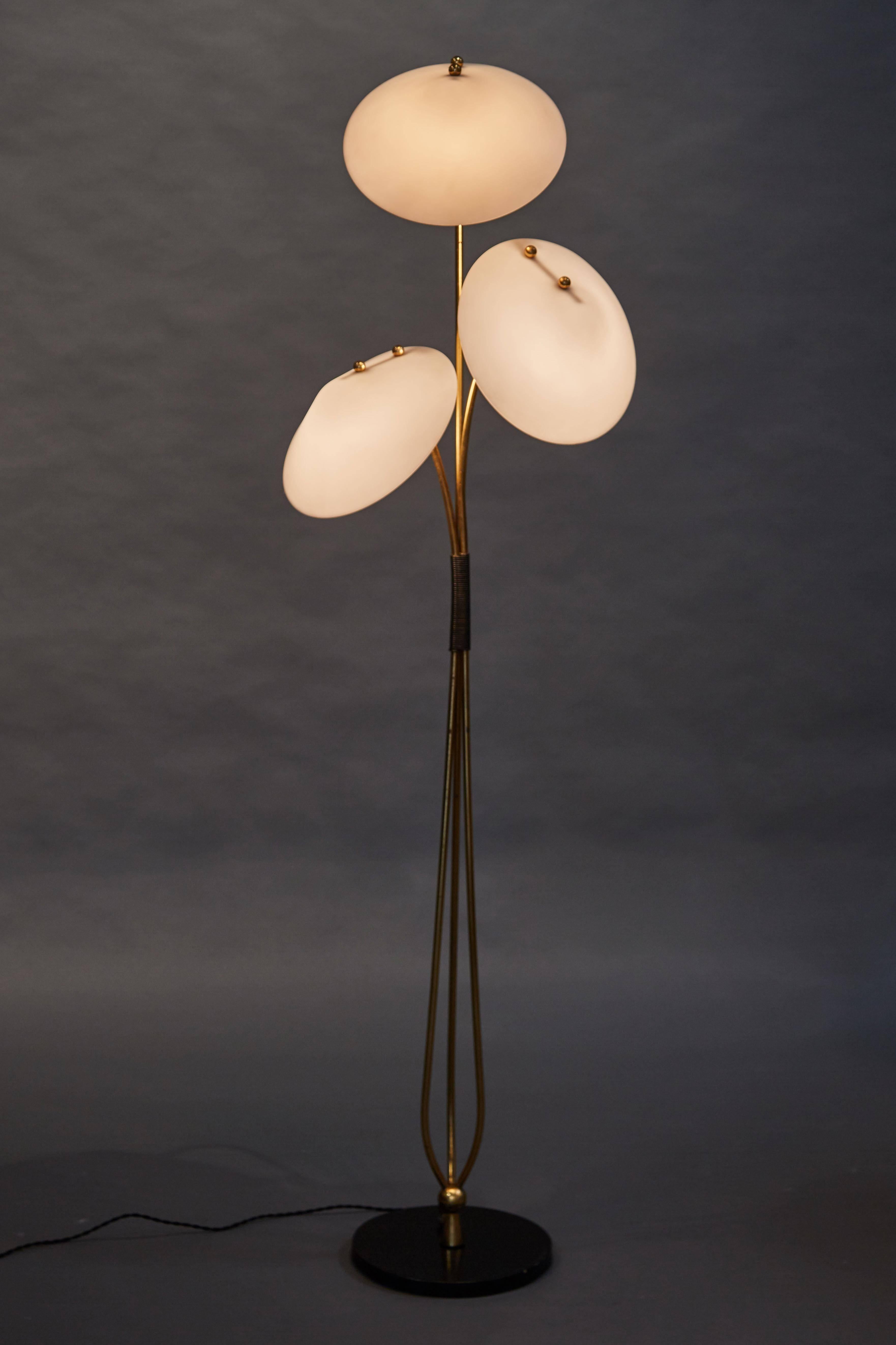 A unique and beautiful French floor lamp with three acrylic pyramidal shades above brass rods and an enameled metal base.