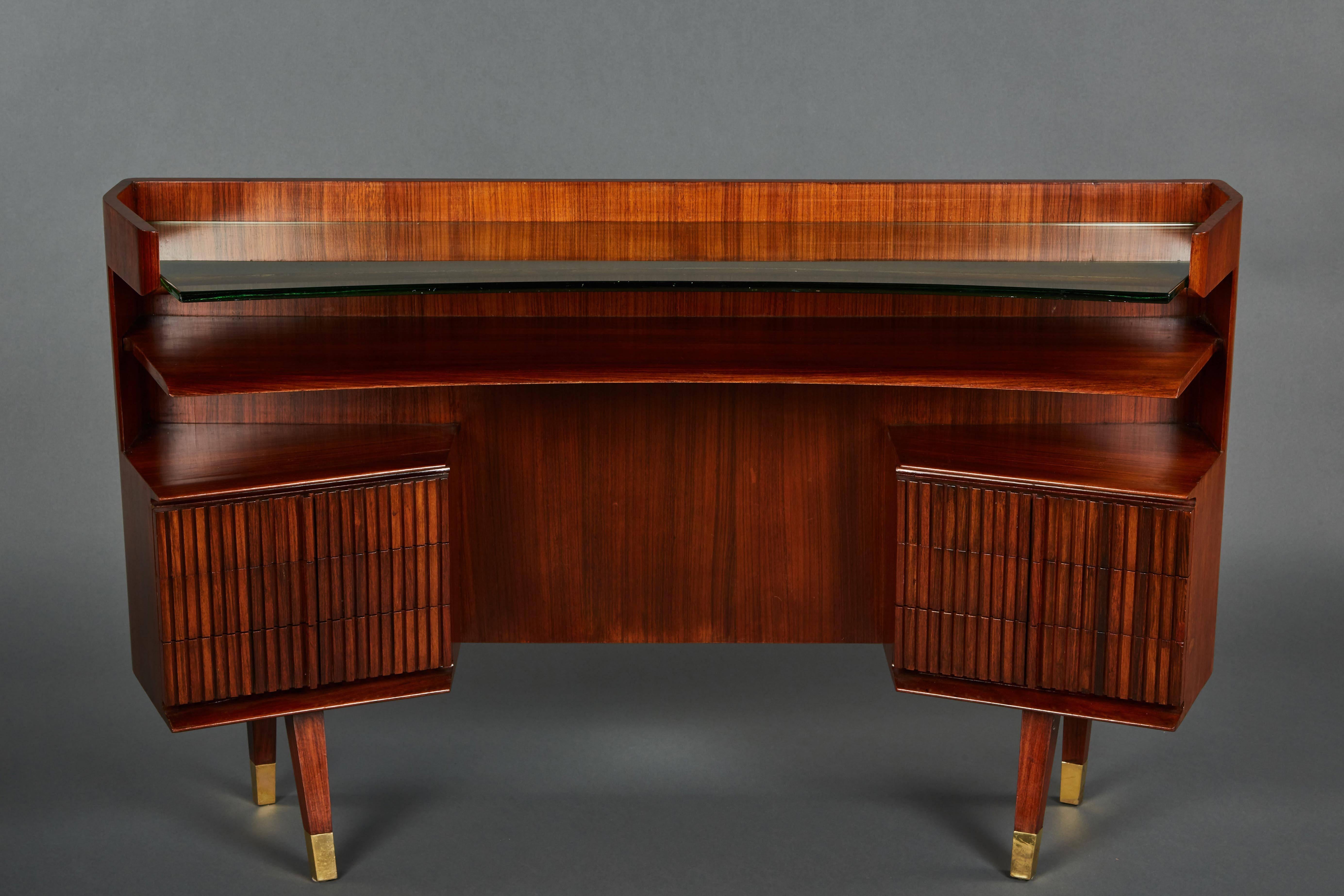 A rare console/desk attributed to Luisa and Ico Parisi. Petite with a curved design and glass top. Each side features a bank of three drawers, exhibiting pleasing, ridged details. Legs are finished with brass sabots. Body of desk is 10” deep.