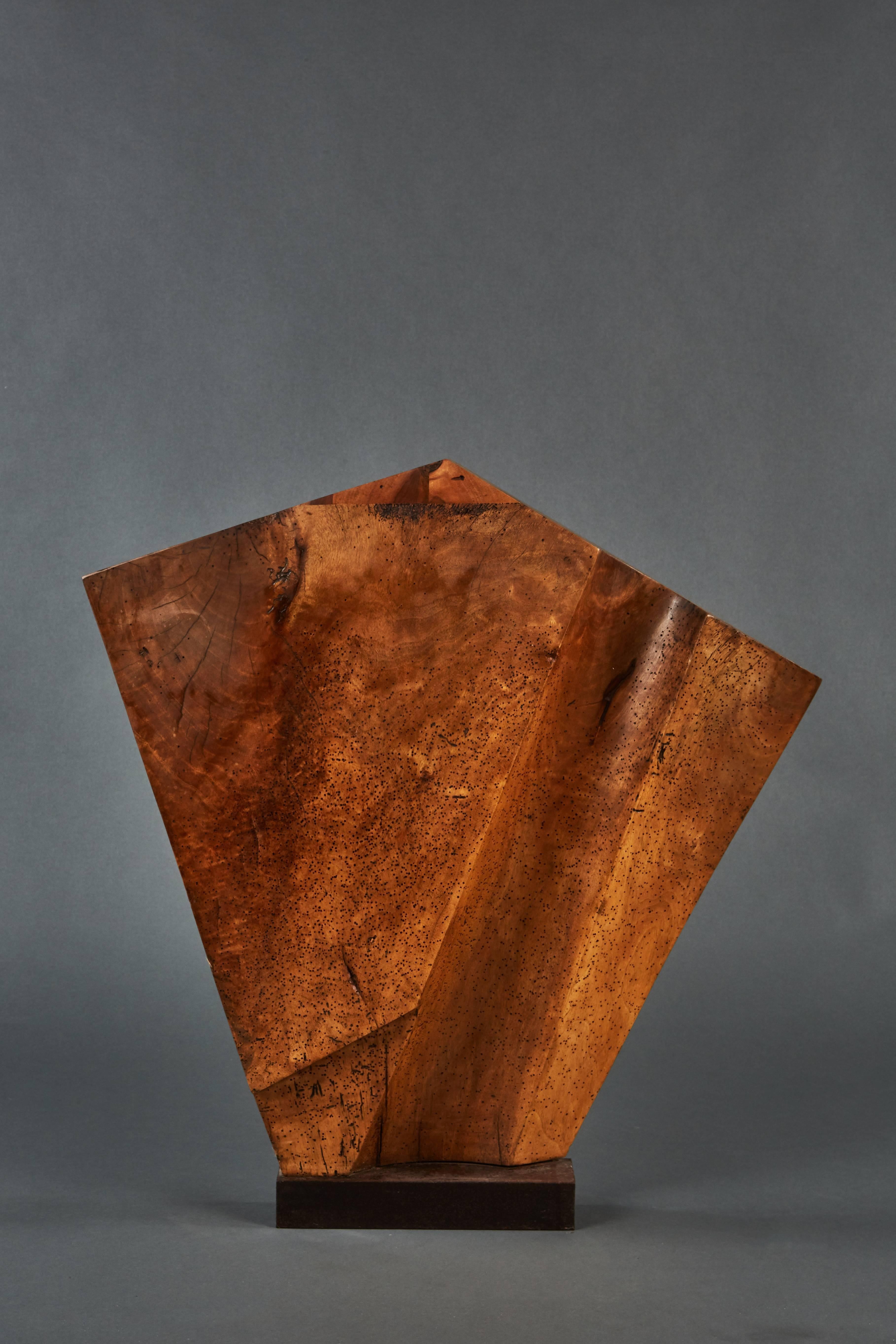 A bold and striking wood sculpture mounted on a metal base.