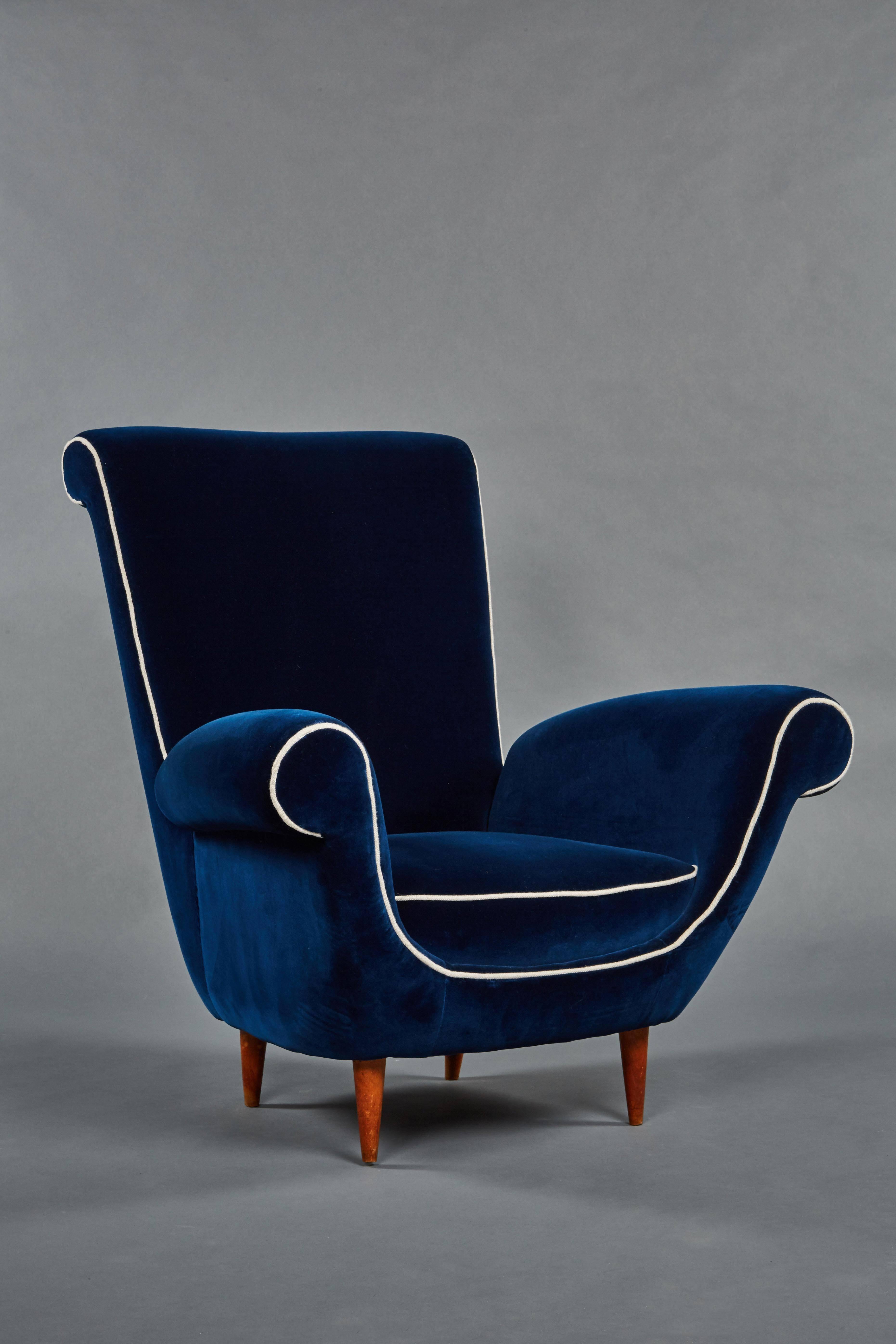 A pair of Ico Parisi attributed blue velvet armchairs. Scrolled details are sharply accentuated by a white linen welt. Mounted on walnut dowel legs.