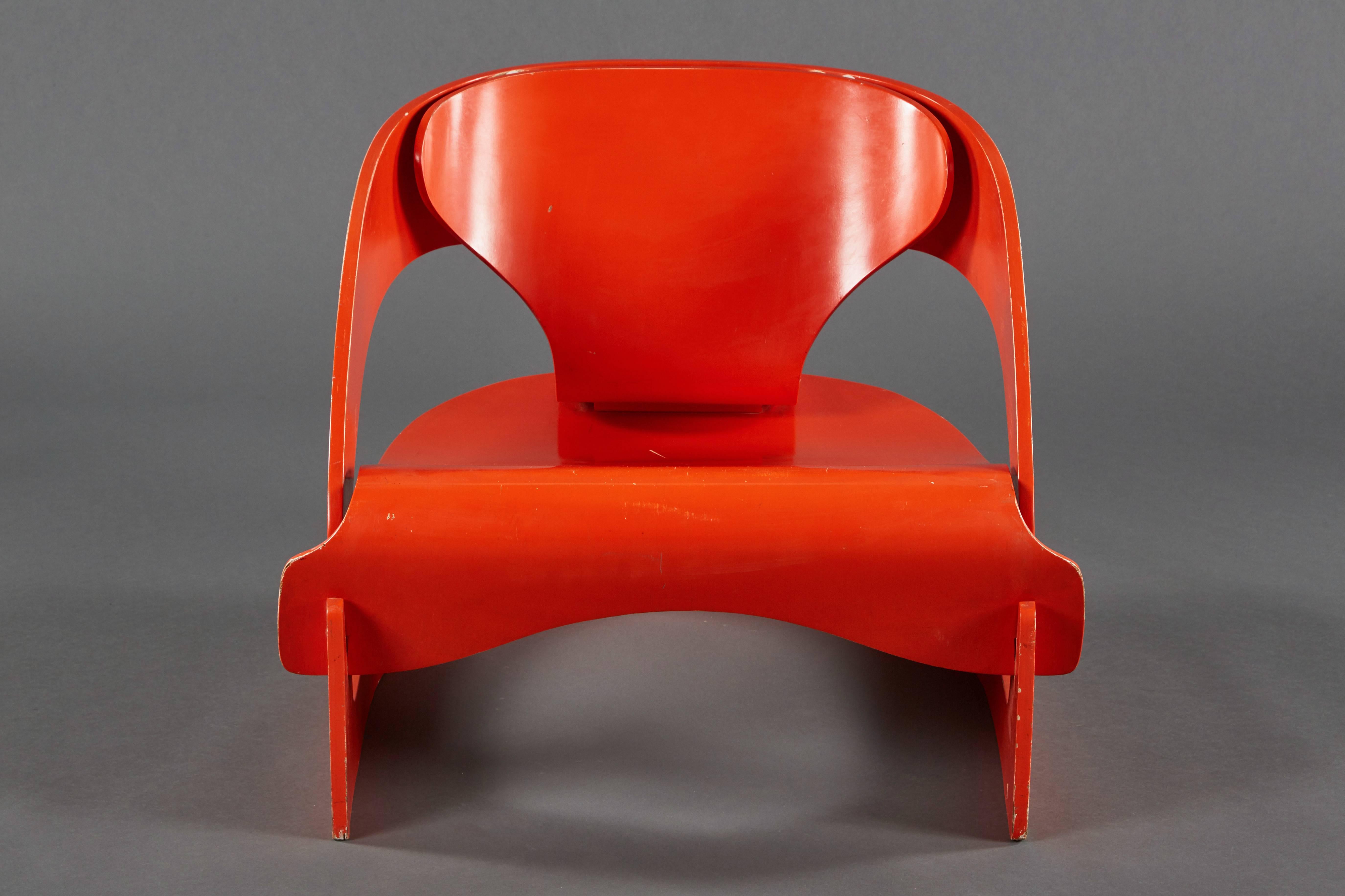 A red lacquered sculptural Joe Colombo No. 4801 “Interlocking” chair. The body is composed of three separate pieces of molded interlocking plywood without any metal fittings. Designed for Kartell in 1963.