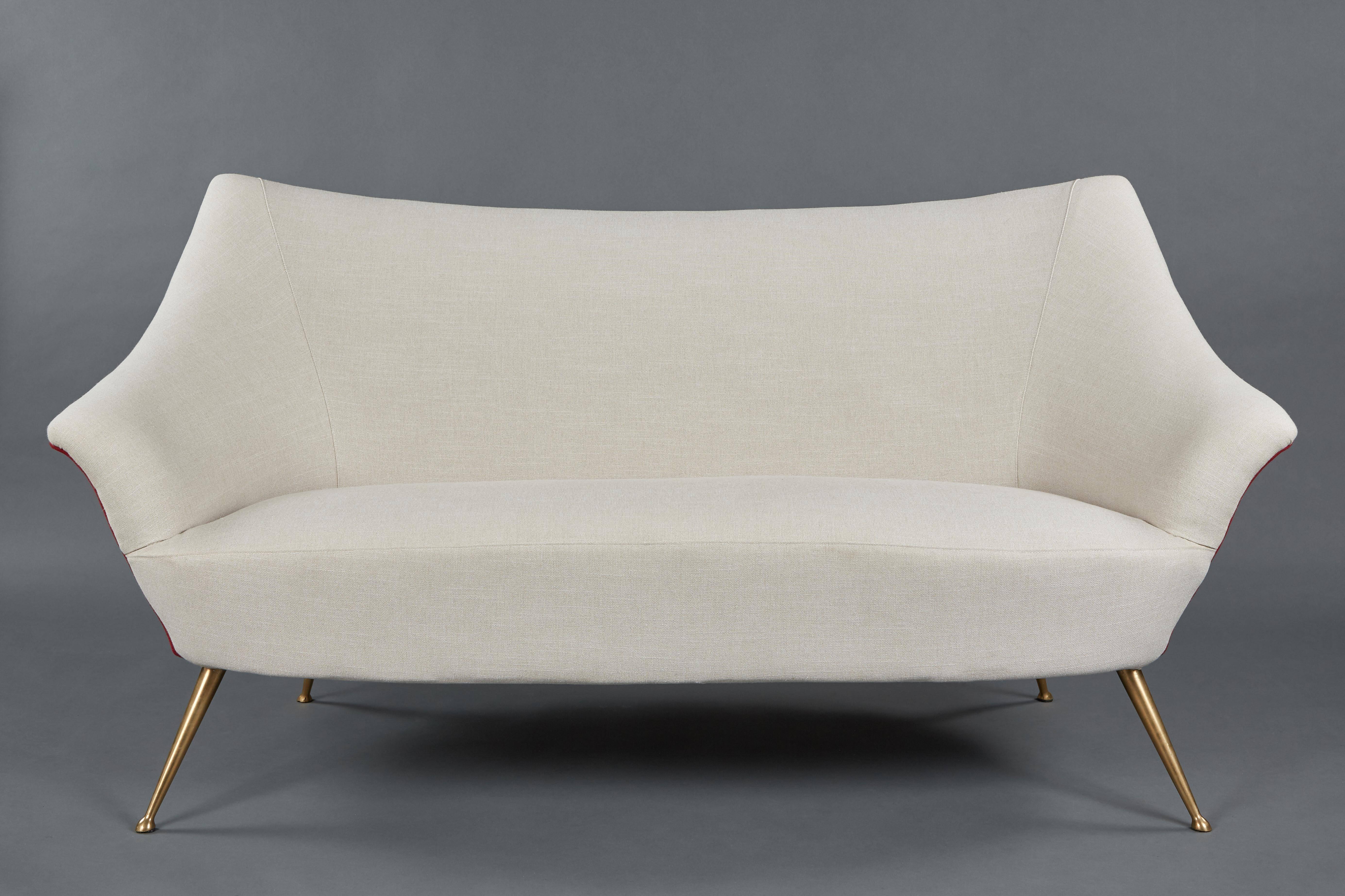 A 1950s, Italian petite sofa and pair of chairs. Suite is newly upholstered in a cream linen with contrasting linen on back and features curvilinear lines with legs gracefully designed in brass.

Dimensions in listing are for sofa. Armchairs