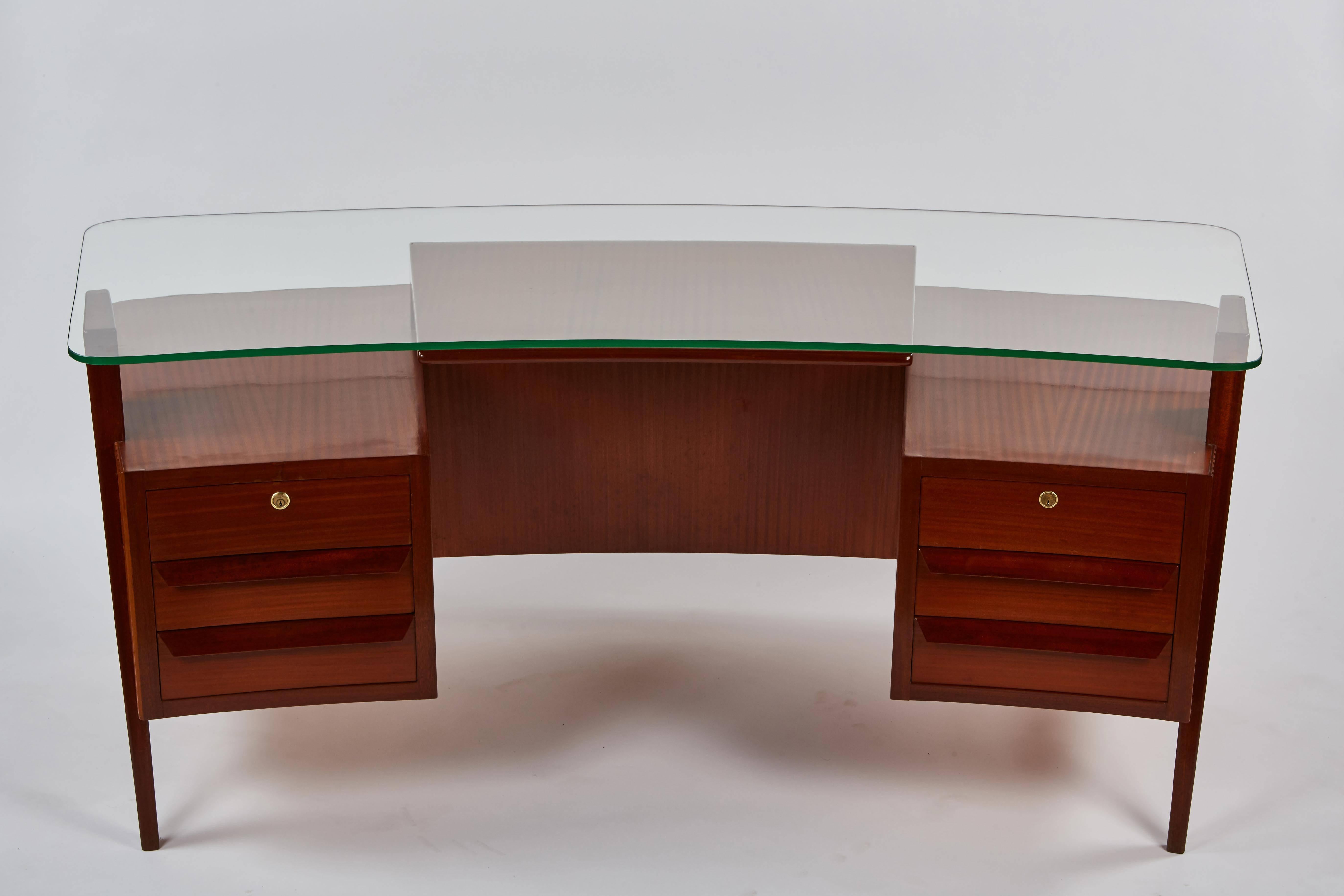 A highly striking, rare and dramatic Carlo de Carli Desk. This curvilinear executive desk is in ribbon mahogany with a glass top. The apron features vertical ridged detailing and four drawers, two of which lock.
