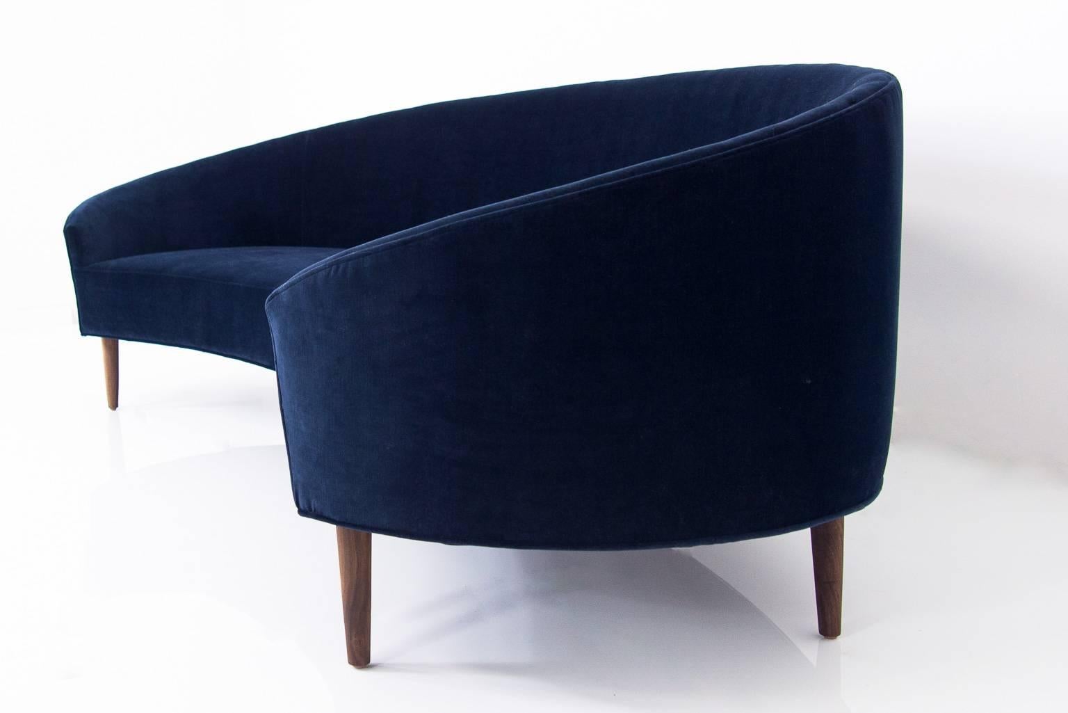 With Classic clean lines and sharp curves comes Modshop's Art Deco sofa. Uniquely shaped, similar to a crescent, curved in arms and six walnut cone legs put together in elegance. Shown in navy velvet.

Measures: 105