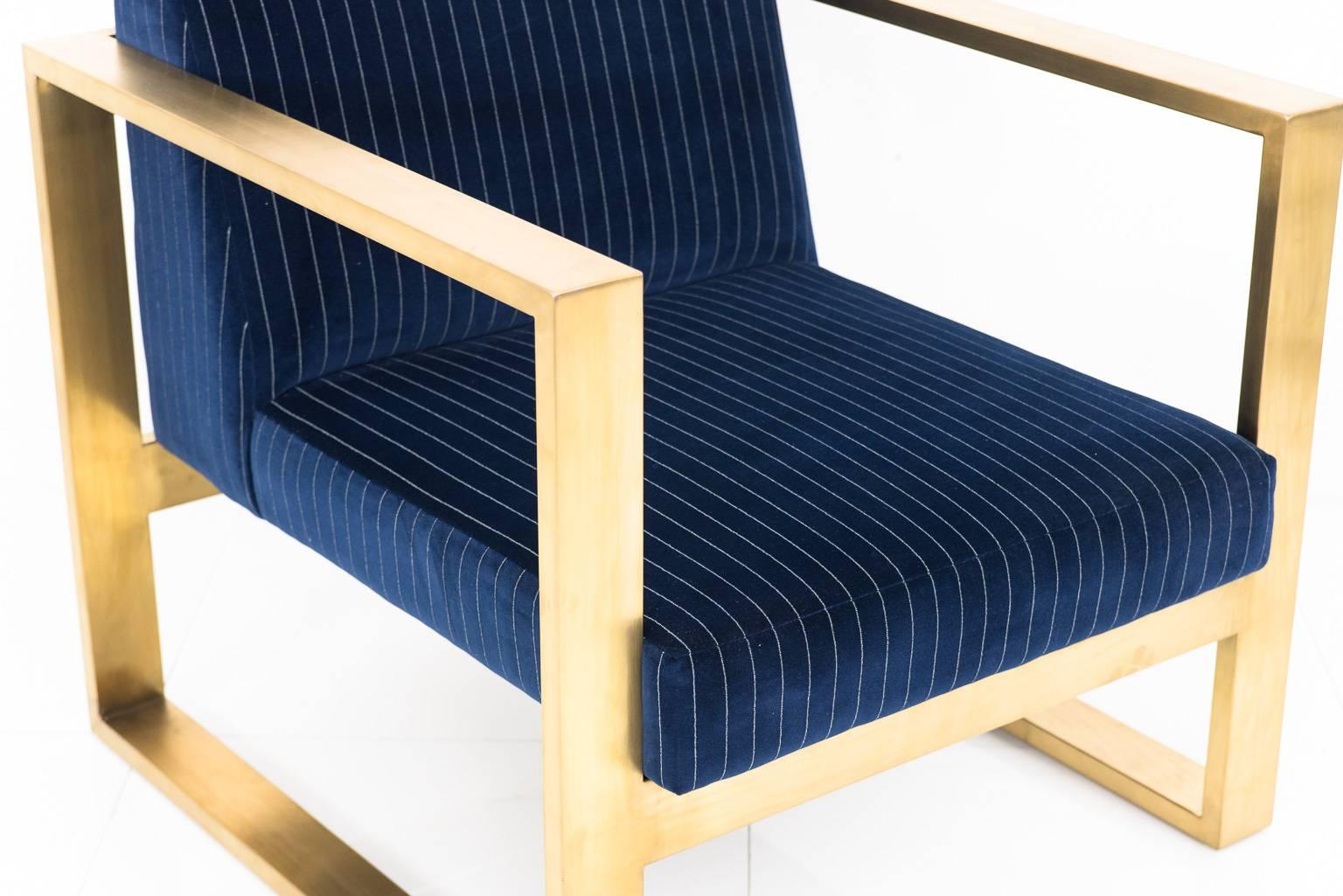 Modshop's Kube chair creates a stunning and comfortable tight seat chair. This is finished in navy pinstriped velvet and brass U-leg frame.