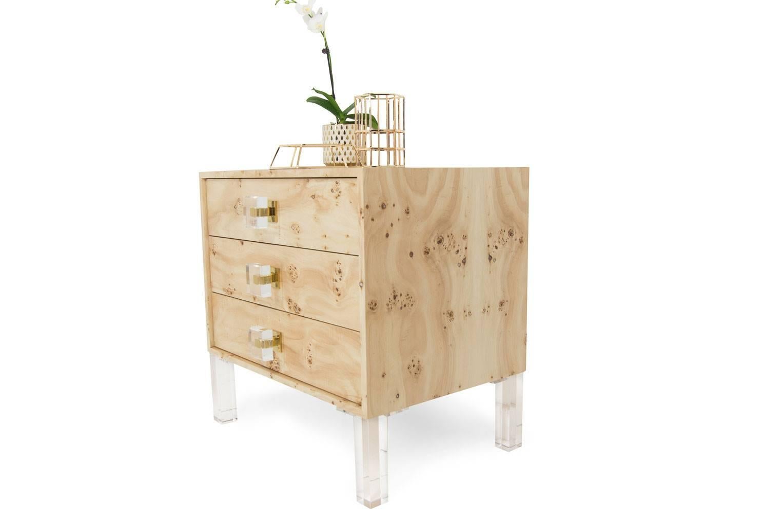Introducing the all new Gold finger Collection. The Gold finger side table is finished in a burl wood veneer, showcasing the natural beauty of this type of wood. The drawers have lucite and brass square pulls, which all sits on top of our lucite