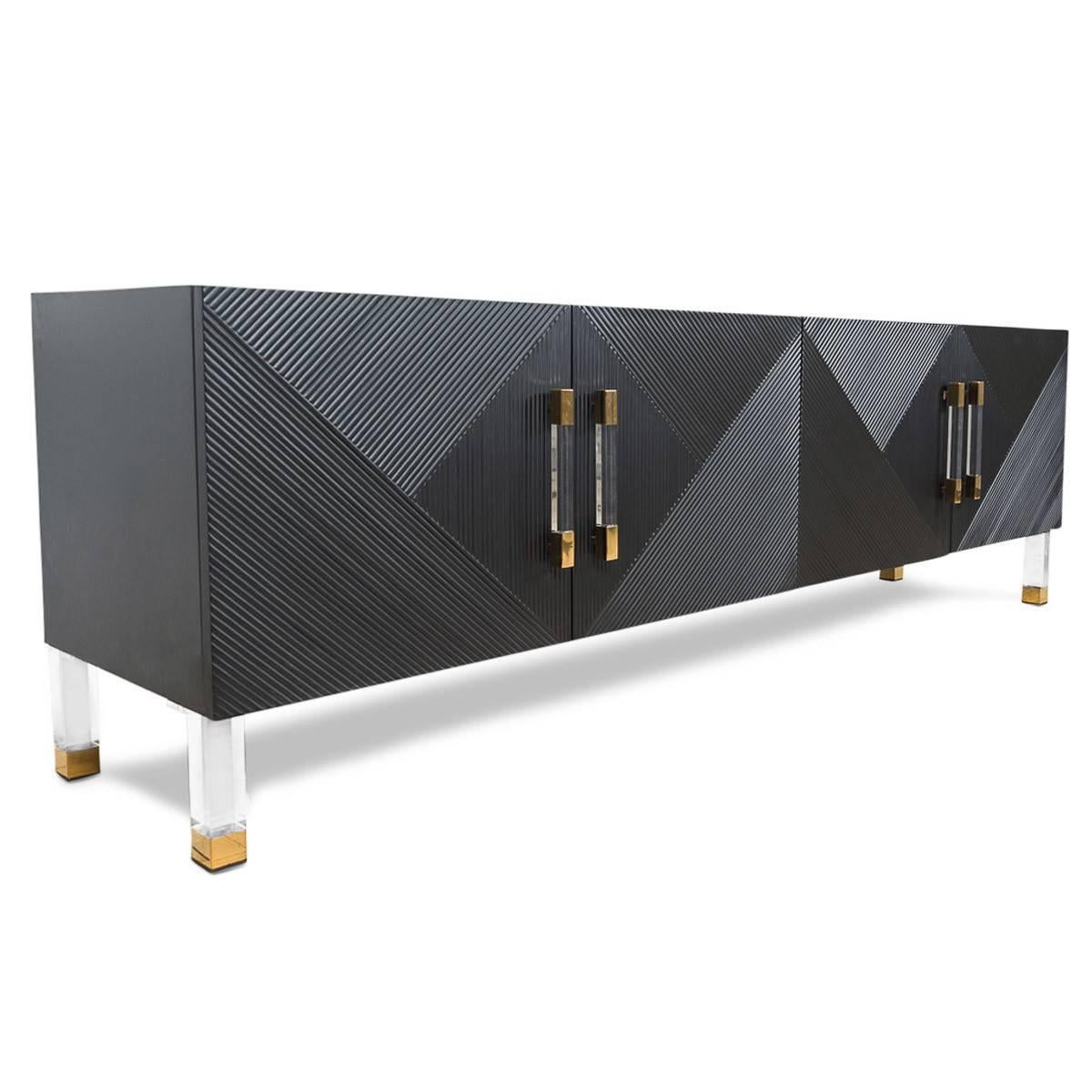 This credenza exudes elegance featuring bevelled line work creating an interesting and unique pattern amongst the facade of this credenza. Along with the Lucite and brass bar pulls and legs, this is sure to make a bold statement in any elegant