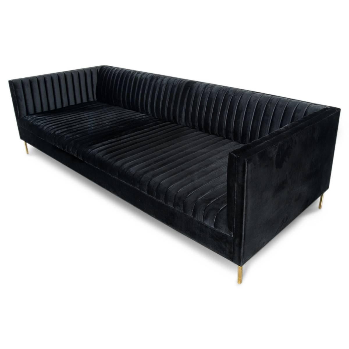 This sofa epitomizes the modern loft lifestyle of the 21st century New Yorker. An economy of style and comfort come together in this beautiful, long arm tufted sofa, shown in black velvet, and L shaped brass legs. Bring some color and sophistication