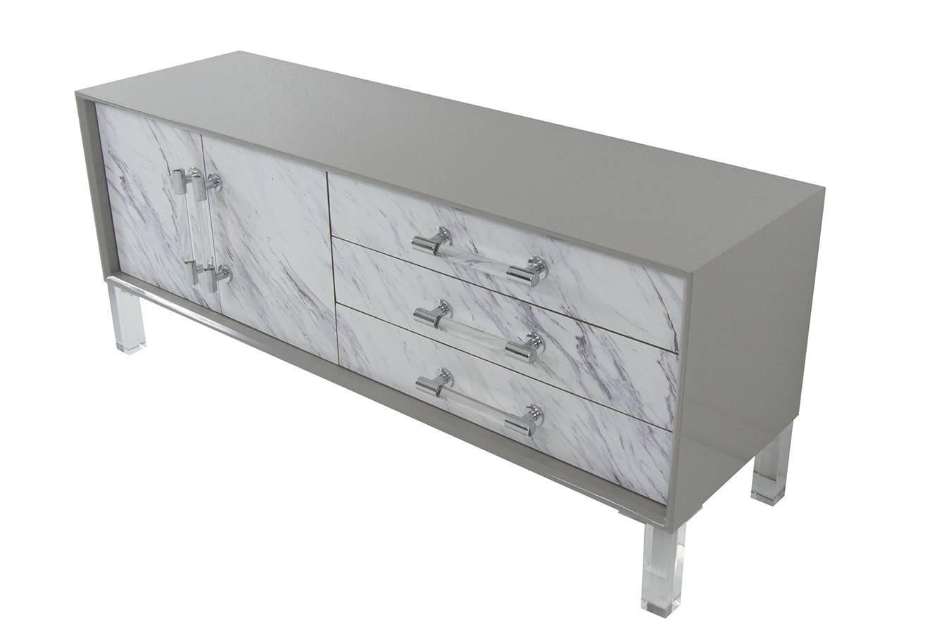 Our stylish new credenza is a class of it's own. The case is made with greystone lacquer finish and is mixed with a faux marble door and drawer fronts. This wood and stone look combination makes the piece a class of it's own. The use of the Lucite