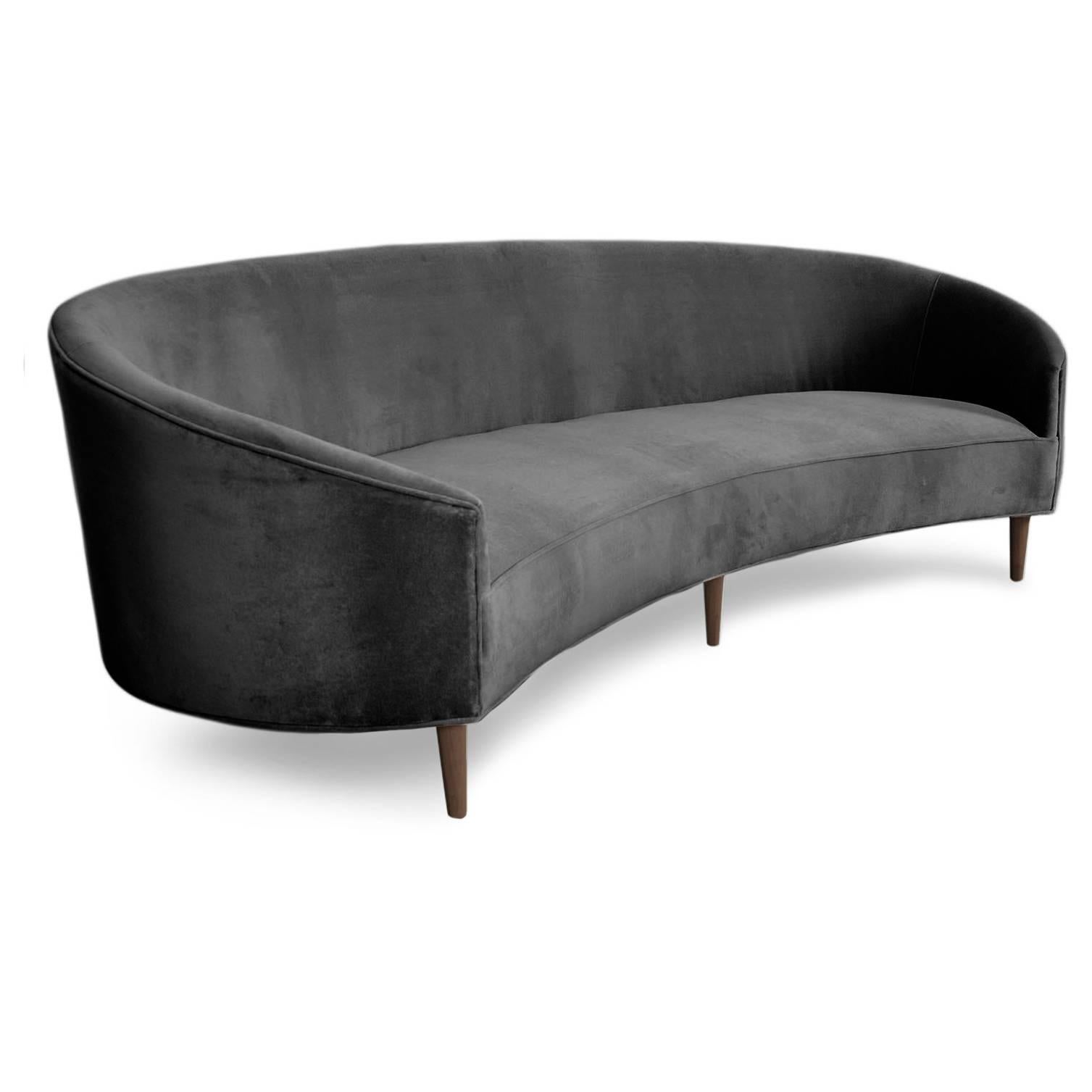 With Classic clean lines and sharp curves comes this Art Deco sofa. Uniquely shaped, similar to a crescent, curved in arms and six walnut cone legs put together in elegance. Shown in Charcoal velvet.

Measures: 105