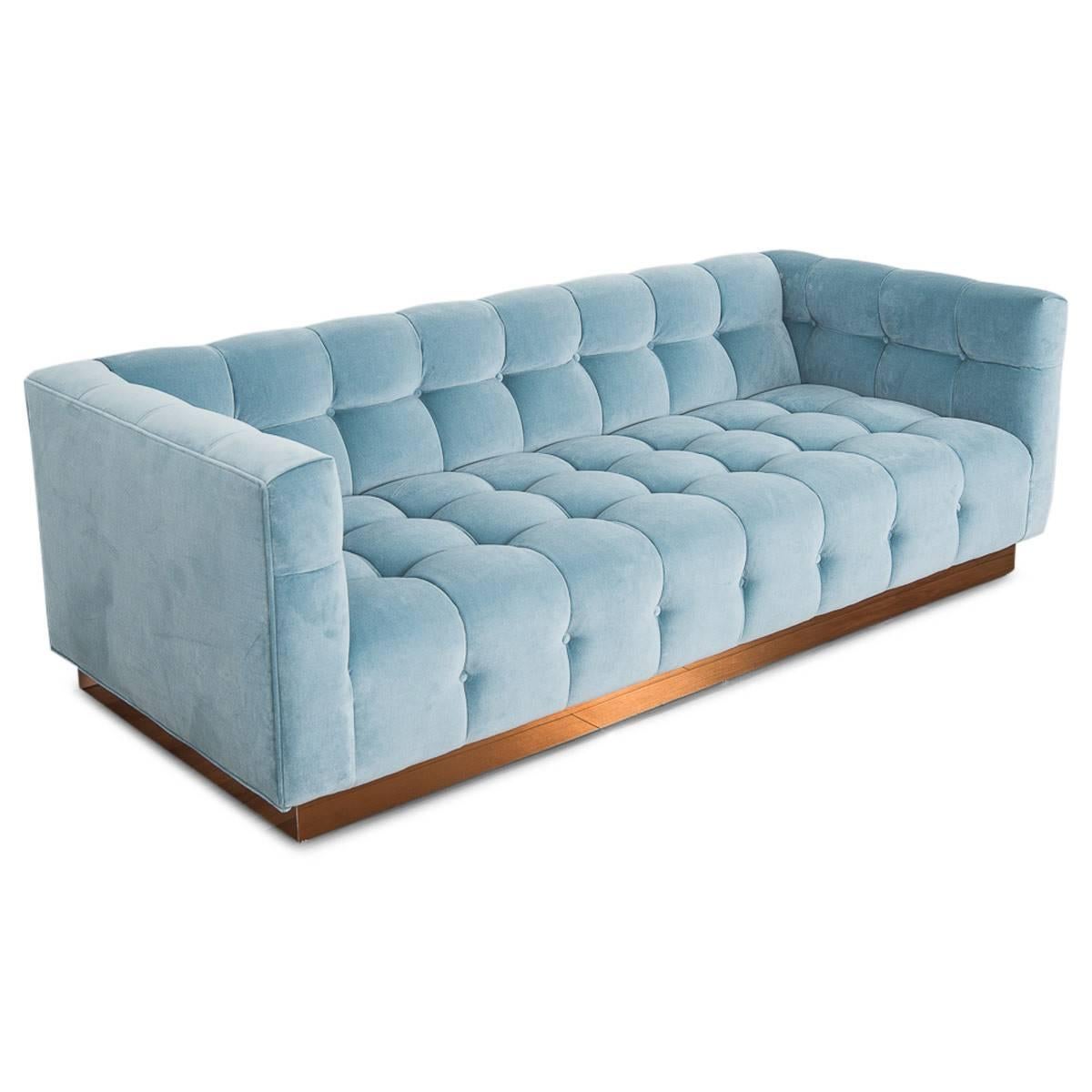 Introducing Modshop's newest addition to our Delano sofa collection. This handcrafted, gem features a copper toekick base and delicately folded biscuit tufting with pulled buttons in a soft light denim blue velvet.