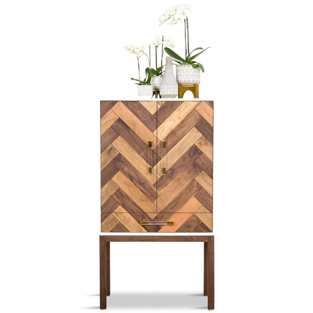 Inspired by the Ionian island, the Corfu bar cabinet takes its cues from the rugged earthy rooftops that adorn the skyline of the island. This motif is repeated in the chevron pattern of the oiled solid walnut. Lucite and shiny brass pulls complete