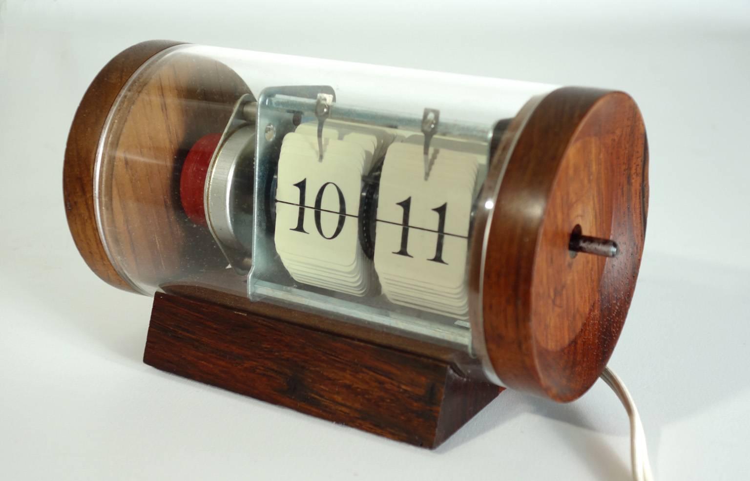 Very rare and desirable Arthur Umanoff flip table clock. When plugged in all moving parts are visible. Made of solid rosewood and glass. A true collectors piece. Signed with decal manufacturer’s label to reverse, Howard Miller Clock Company Zeeland