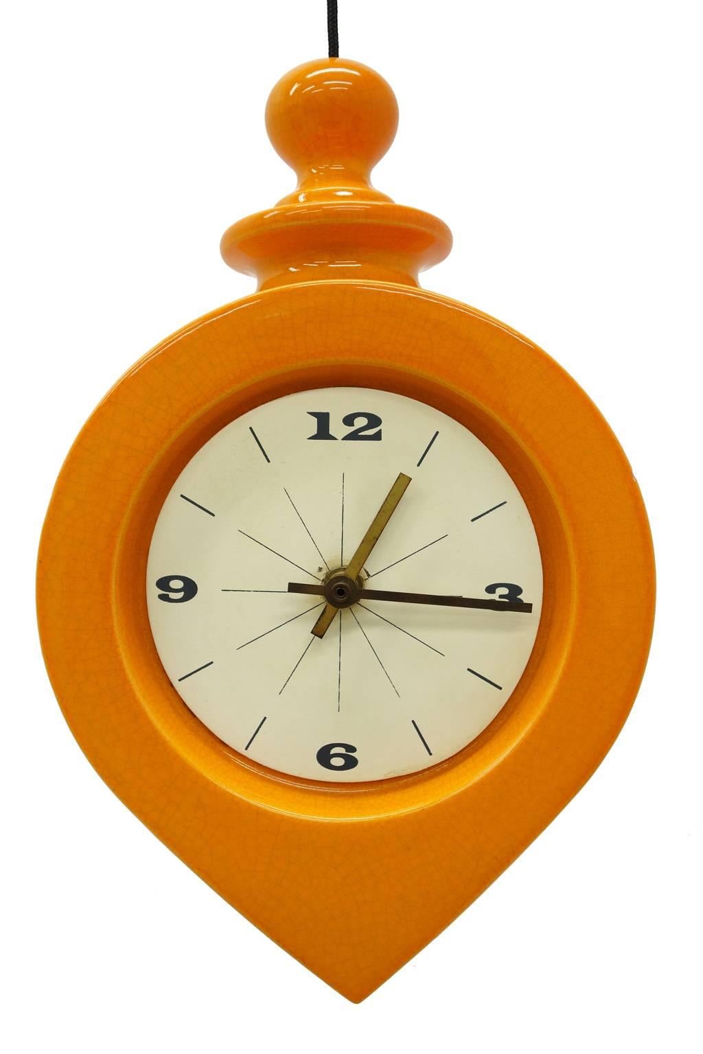 Amazing 1970s design hanging clock by Charles Chaney. Heavy ceramic with bright orange glaze. This clock can be wall-mounted or hang at adjustable heights. Comes with two extra interchangeable clock faces. Clock mechanism is made in Germany that