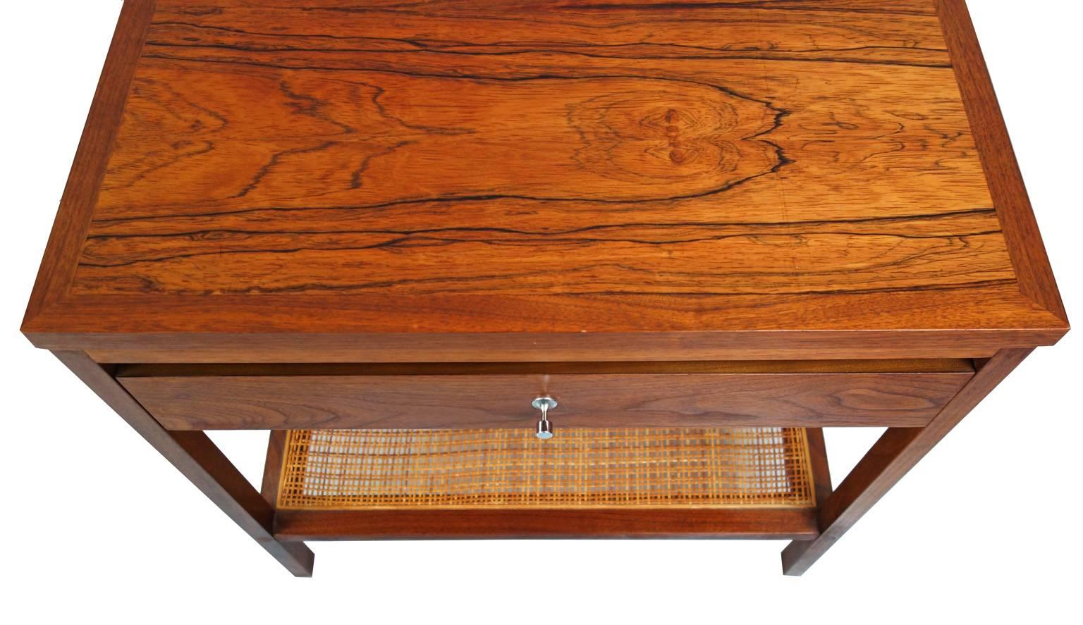 Beautiful pair of Mid-Century end tables comprised of a walnut and rosewood with a caned lower shelf. Designed by Paul McCobb 
